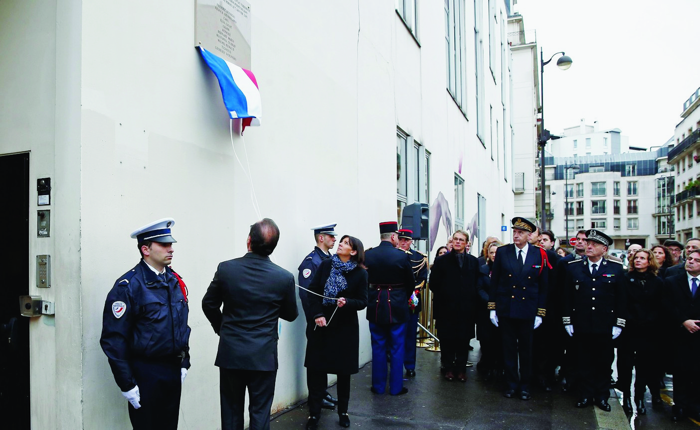 epa05088237 French President Francois Hollande (2-L, back to camera) and Paris Mayor Anne Hidalgo (C) unveil a commemorative plaque outside the former offices of French weekly satirical newspaper Charlie Hebdo during a ceremony to pay tribute to the victims of the last year's January attacks in Paris, France, 05 January 2016. The name of late French cartoonist Georges Wolinski has been mispelled 'Wolinsky'. France this week commemorates the victims of last year's Islamist militant attacks on satirical weekly Charlie Hebdo and a Jewish supermarket with eulogies, memorial plaques and another cartoon lampooning religion.  EPA/BENOIT TESSIER / POOL MAXPPP OUT