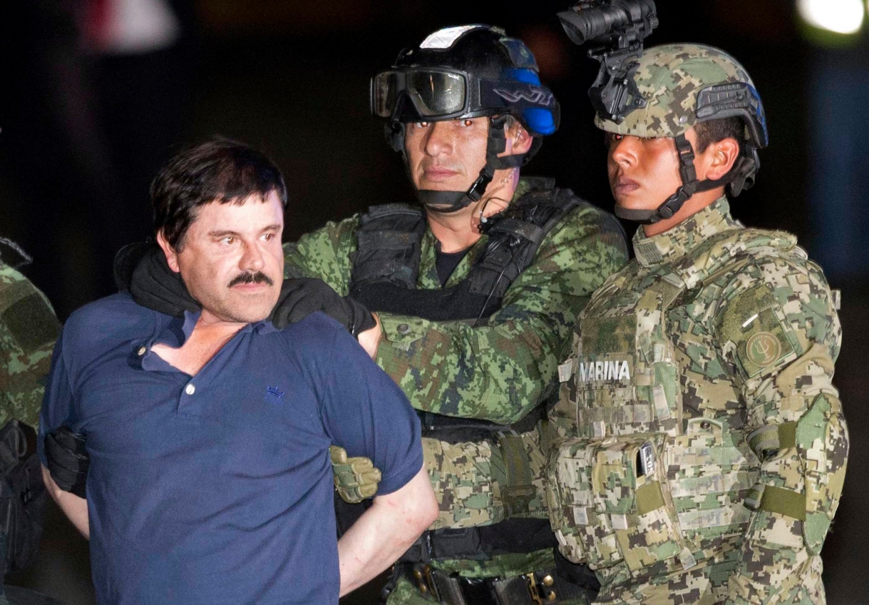 In this Friday, Jan. 8, 2016 photo, Joaquin "El Chapo" Guzman is made to face the press as he's escorted to a helicopter in handcuffs by soldiers and marines at a federal hangar in Mexico City. Guzman's second prison escape in 2015 from a top security prison though a tunnel had embarrassed President Enrique Pena Nieto and made his capture a national priority. (AP Photo/Eduardo Verdugo) The Week That Was in Latin America Photo Gallery