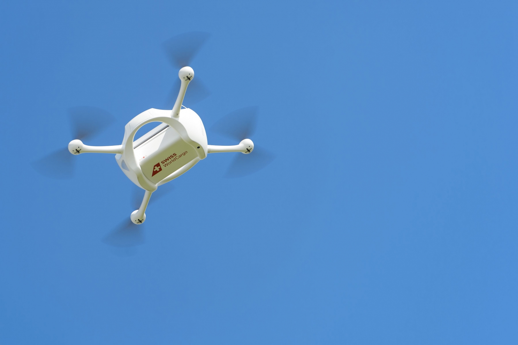 Un drone vole pilote par une personne lors d'une presentation par la Poste d'une livraison de paquets a l'aide de drones ce mardi 7 juillet 2015 a Bas-Vully. La Poste suisse, Swiss WorldCargo, (la division de fret aerien de Swiss) et Matternet, (un fabricant de drones base en Californie), ont lance un projet commun afin de tester l'utilisation de drones pour la livraison des paquets. (KEYSTONE/Jean-Christophe Bott)