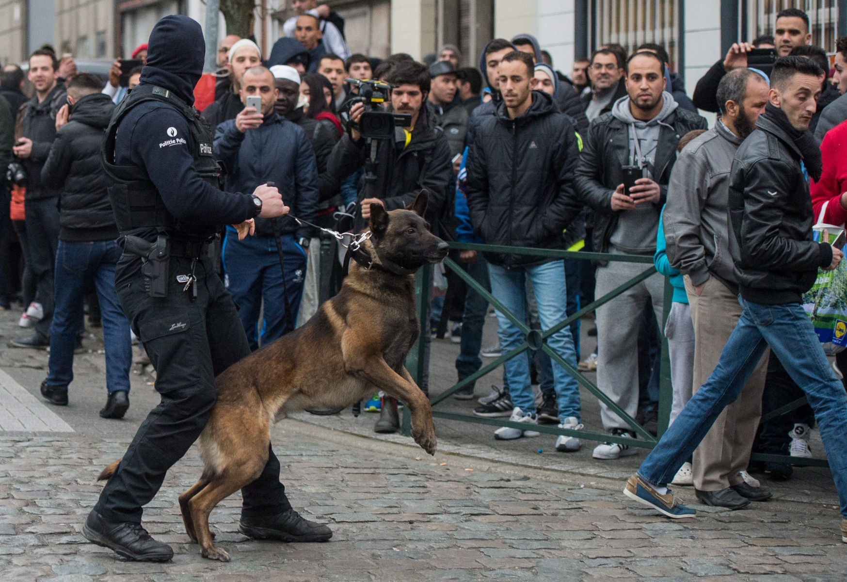 epa05218780 A Belgian police dog handler holds back curious onlookers during an anti-terror operation in the Molenbeek neighborhood of Brussels, Belgium, 18 March 2016. Media reports claim that fugitive terror suspect Salah Abdeslam has been wounded but arrested alive during the anti-terror operation in Molenbeek that was carried out within the investigations linked to last year's Paris terror attacks.  EPA/STEPHANIE LECOCQ BELGIUM TERRORIST RAID