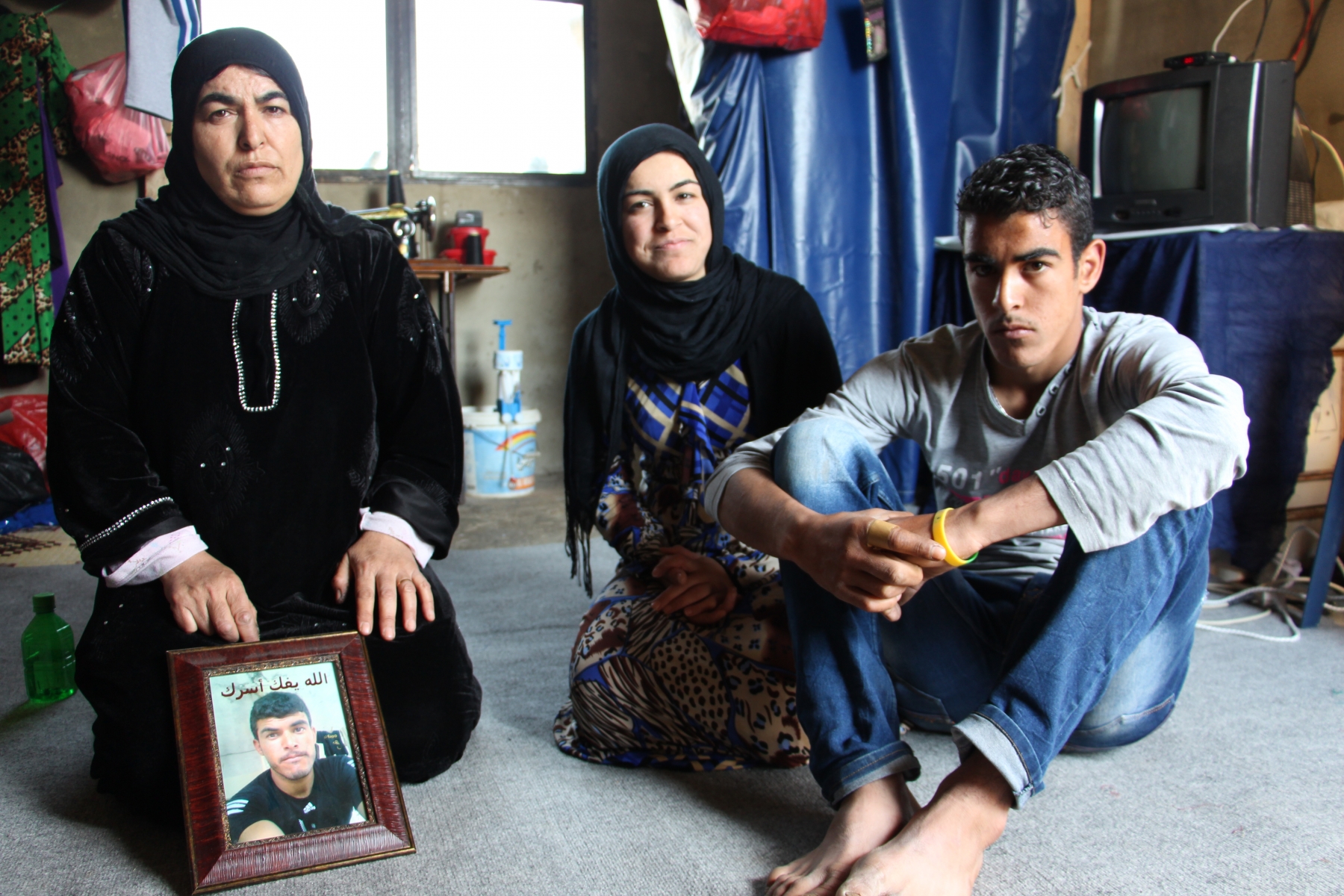 Wael (prénom d'emprunt) avec sa mère, sa sœur, et le portrait de son frère emprisonné en Syrie.