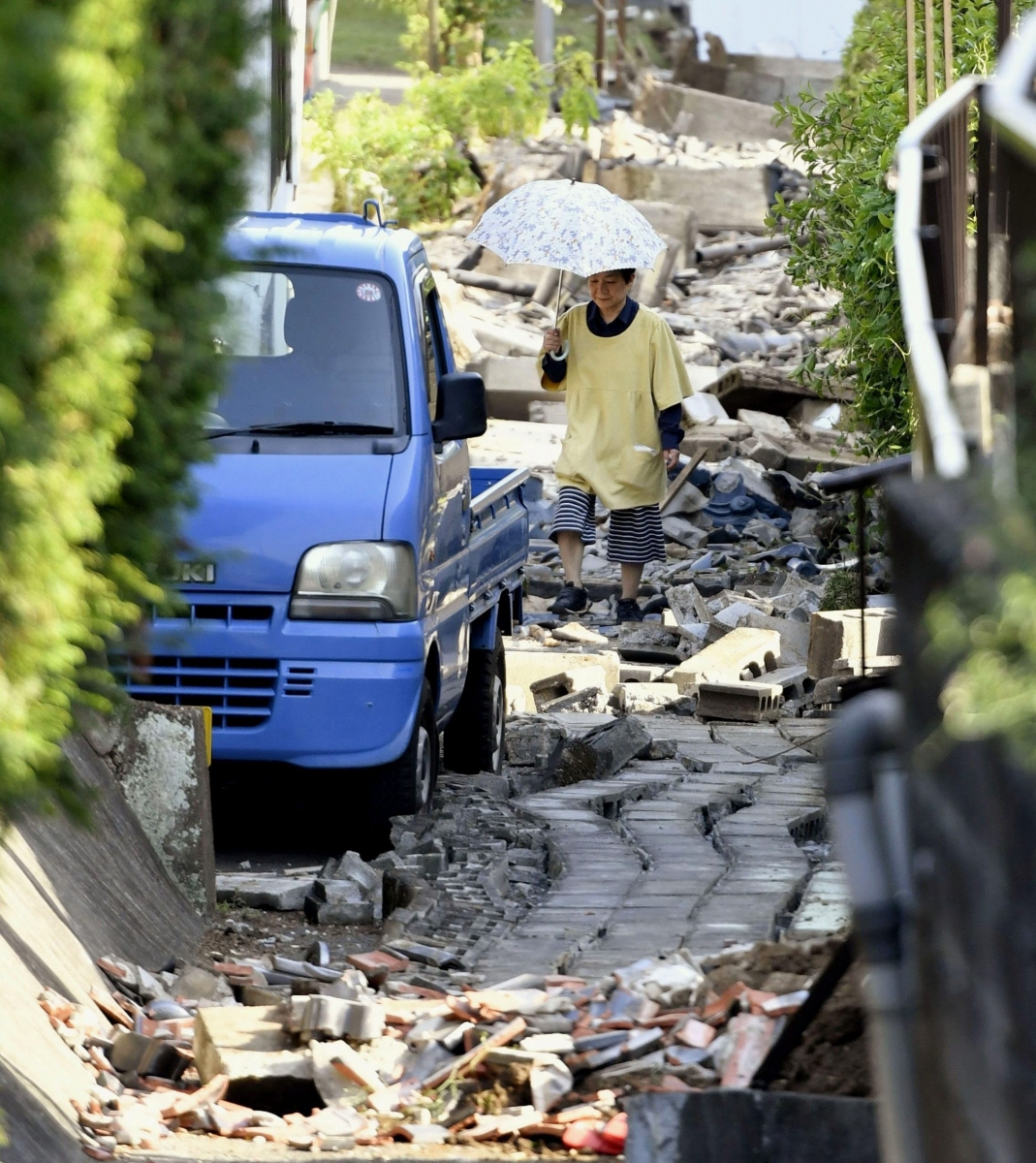 A resident walks through the debris after a magnitude-6.5 earthquake in Mashiki, Kumamoto prefecture, southern Japan, Friday, April 15, 2016.  More than 100 aftershocks from Thursday night's earthquake continued to rattle the region as businesses and residents got a fuller look at the widespread damage from the unusually strong quake, which also injured about 800 people. (Kyodo News via AP) JAPAN OUT, MANDATORY CREDIT Japan Earthquake