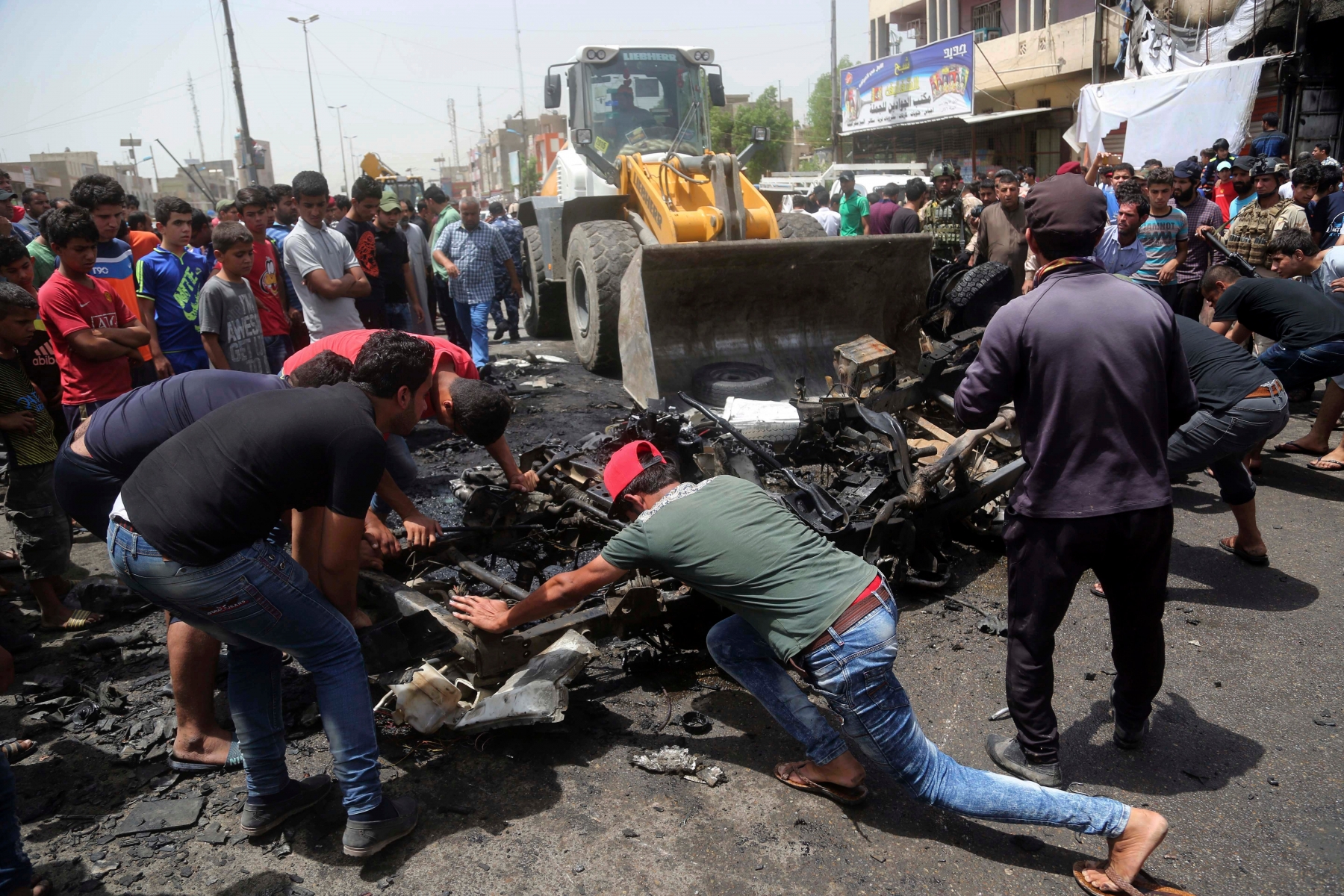 Civilians help a municipality bulldozer cleans up while citizens inspect the scene after a car bomb explosion at a crowded outdoor market in the Iraqi capital's eastern district of Sadr City, Iraq, Wednesday, May 11, 2016. An explosives-laden car bomb ripped through a commercial area in a predominantly Shiite neighborhood of Baghdad on Wednesday, killing and wounding dozens of civilians, a police official said. (AP Photo/ Khalid Mohammed) Mideast Iraq