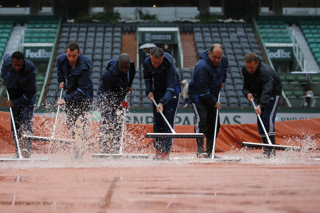 Les employés chargés d'évacuer l'eau des bâches ont remplacé les joueurs sur les courts.