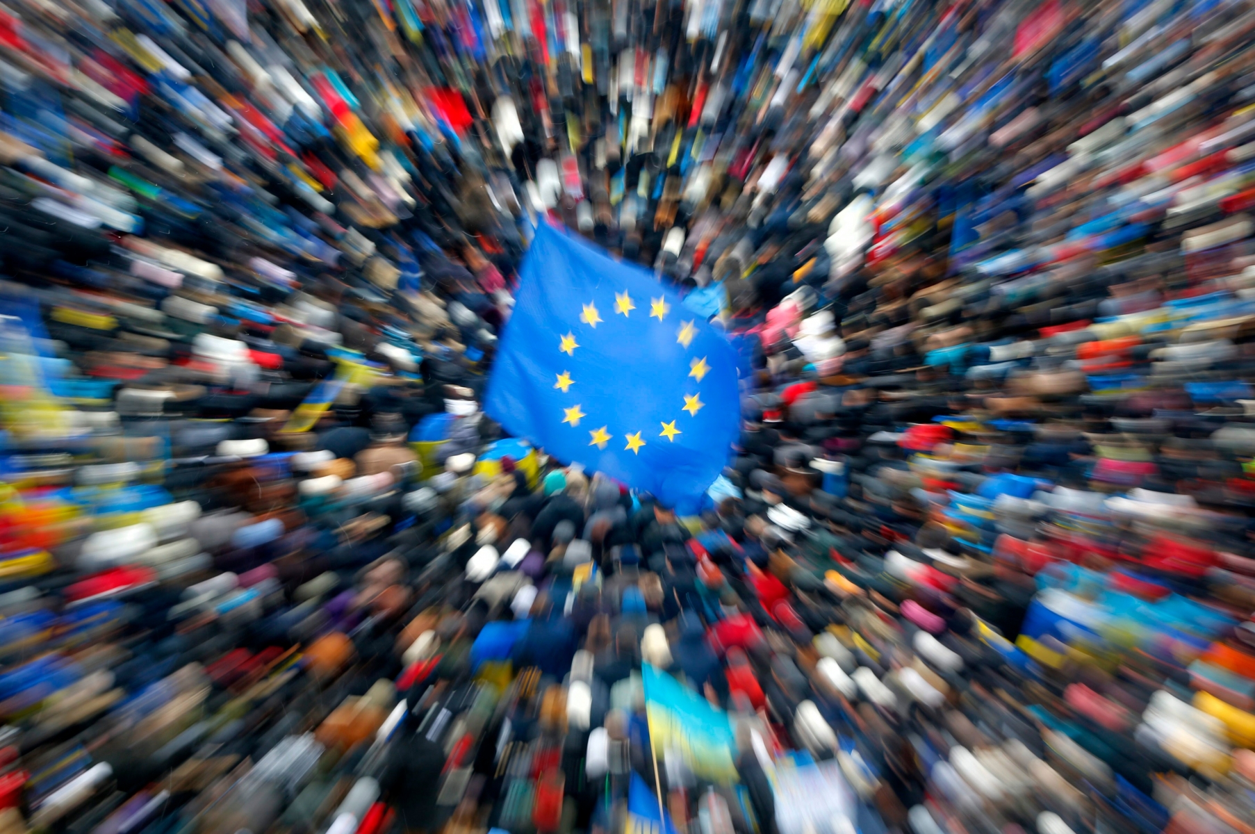 A European Union flag flies above a crowd of Pro-European Union activists gather during a rally in the Independence Square in KIev, Ukraine, Sunday, Dec. 8, 2013. The third week of protests continue Sunday with an estimated 200,000 Ukrainians occupying central Kiev to denounce President Viktor Yanukovychís decision to turn away from Europe and align this ex-Soviet republic with Russia.  (AP Photo/Sergei Grits) EDS NOTE PHOTO TAKEN WITH ZOOM LENS AND LONG EXPOSURE  Ukraine Protest