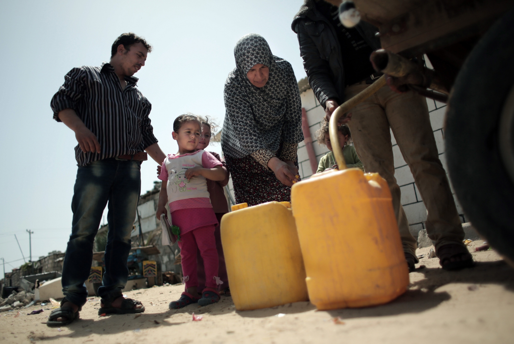 In this Saturday, April 16, 2016 photo, A Palestinian family fill plastic gallons with drinking water they bought from a vendor in Khan Younis refugee camp, southern Gaza Strip. Poor sewage has damaged Gaza's limited fresh water supplies, decimated fishing zones, and after years of neglect, is now floating northward and affecting Israel as well, where a nearby desalination plant was forced to shut down, apparently due to pollution. (AP Photo/Khalil Hamra) PALAESTINA ABWASSER
