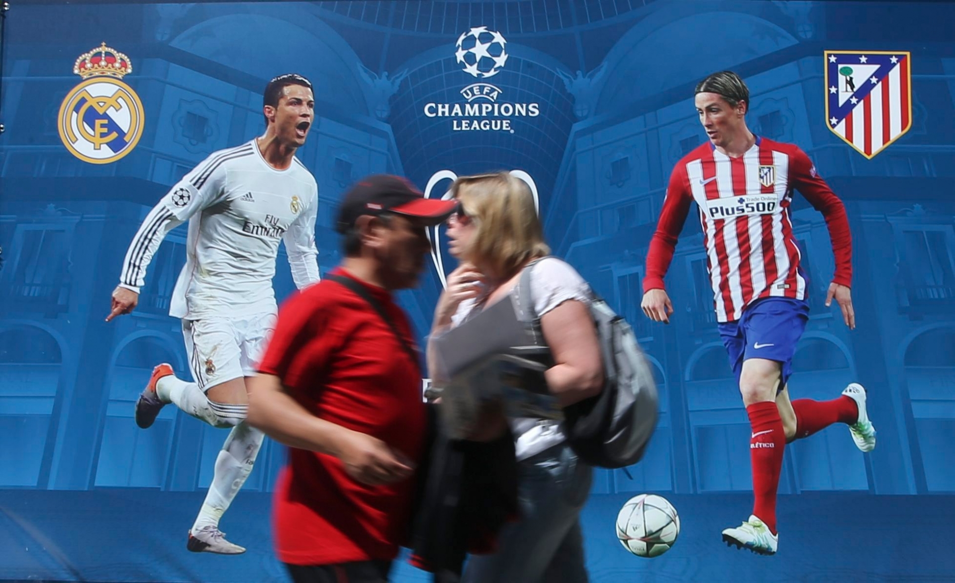 People walk by a billboard portraying Real Madrid's Cristiano Ronald, left, and Athletico Madrid's Fernando Torres, at the Champions Festival event area, in Milan, Italy, Thursday, May 26, 2016. The Champions League soccer final between Real Madrid and Atletico Madrid will be held at the San Siro stadium on Saturday, May 28, 2016. (AP Photo/Luca Bruno) Italy Soccer Champions League Final