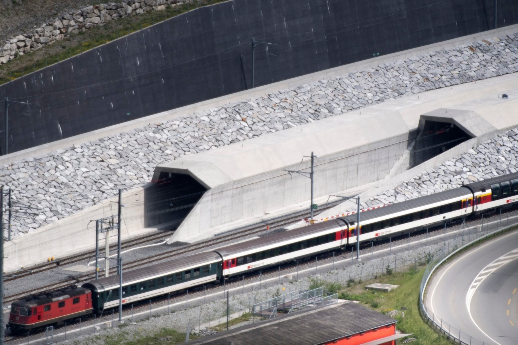 A train passes in front of the northern portal of the Gotthard Base Tunnel on the eve of its inauguration, in Erstfeld, Canton of Uri, Switzerland, Tuesday, May 31, 2016. The Gotthard Base Tunnel, world's longest railway tunnel, consists of two 57-kilometres-long single-track tubes. It joins the north portal at Erstfeld to the south portal at Bodio. The inauguration of the Gotthard Base Tunnel takes place on June 1st. (KEYSTONE/Laurent Gillieron) SWITZERLAND GOTTHARD TUNNEL OPENING