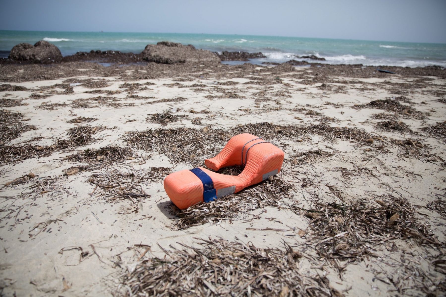 epa05343251 A buoyancy aid lies on a beach where bodies of migrants washed up, in Zuwarah, west of Tripoli, Libya, 02 June 2016. According to media reports citing Red Crescent officials, at least 85 bodies have washed up onto Libyan beaches this week.  EPA/MOHAME BEN KHALIFA LIBYA REFUGEES MIGRATION