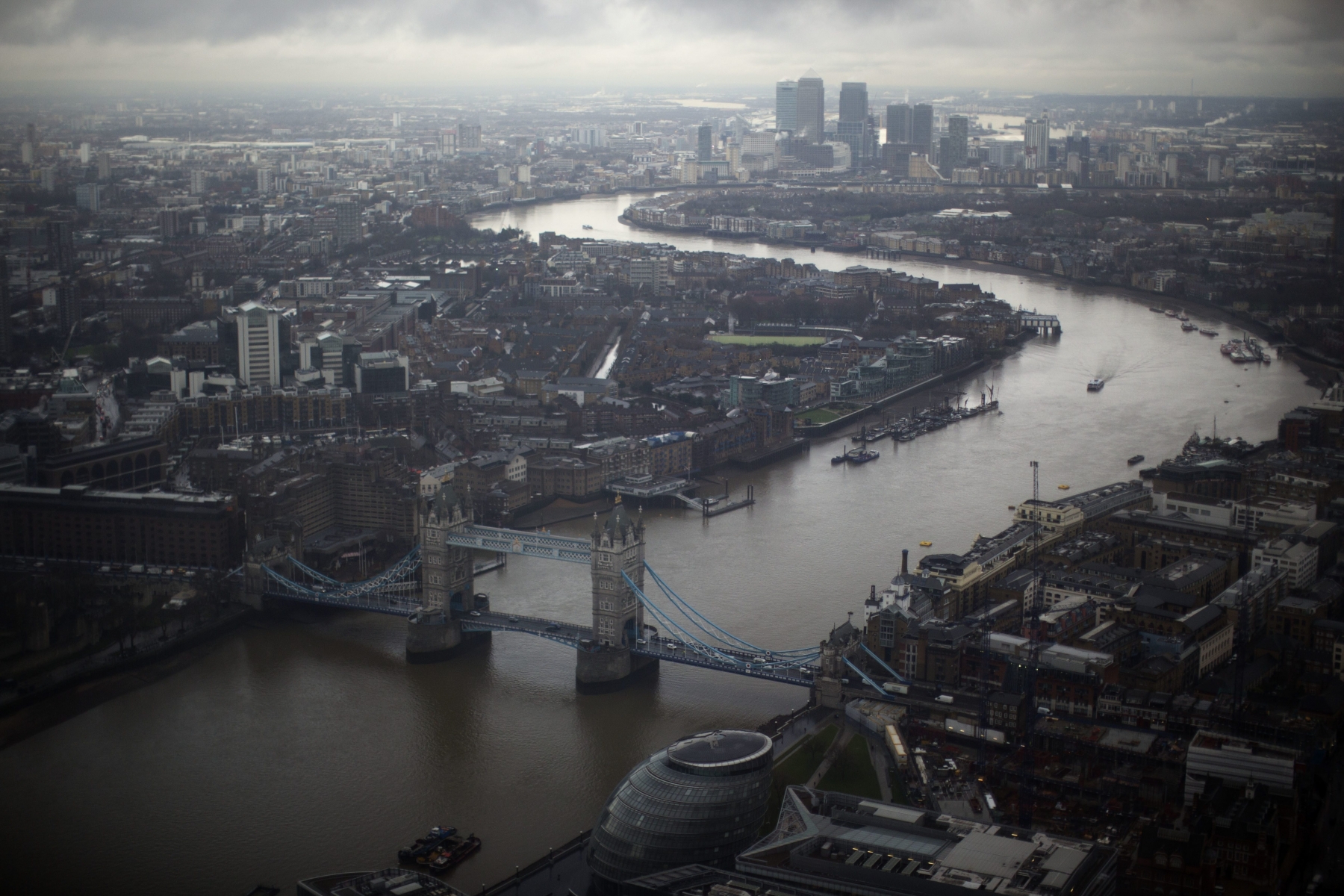 FILE - In this file photo dated Friday, Feb. 1, 2013, Tower Bridge, centre, and the Canary Wharf business district in the distance as the River Thames flows through London, are seen through a window during the official opening of "The View" viewing platform at the 95-storey Shard skyscraper in London, Friday, Feb. 1, 2013.  From the international banks in the skyscrapers of Canary Wharf to the traditional home of Britainís financial industry in the City of London, bankers and money managers across the capital are watching the upcoming June 23 referendum on EU membership with trepidation. (AP Photo/Matt Dunham, FILE) Britain EU The City