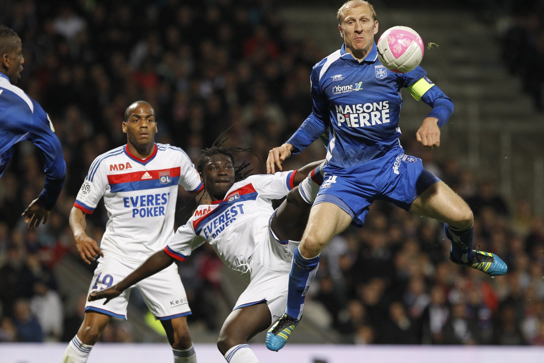 Lyon's Bafe Gomis, center, challenges for the ball with Auxerre's Stephane Grichting, right, during their French League One soccer match at Gerland stadium, in Lyon, central France, Saturday, April 7, 2012. (AP Photo/Laurent Cipriani)