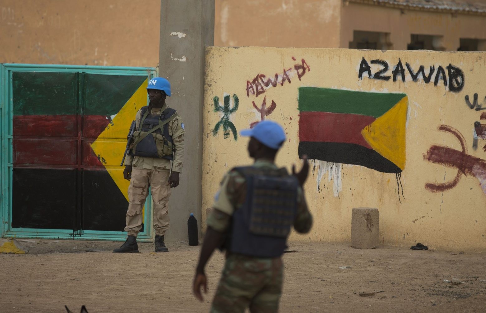 In this July, 27, 2013 photo, United Nations peacekeepers stand guard at the entrance to a polling station covered in separatist flags and graffiti supporting the creation of the independent state of Azawad, in Kidal, Mali. A bomb explosion killed several members of the U.N. peacekeeping mission in Mali in the troubled northern city of Kidal, a spokesman for the mission said Saturday, Dec. 14, 2013. (AP Photo/Rebecca Blackwell) MALI ATTACK