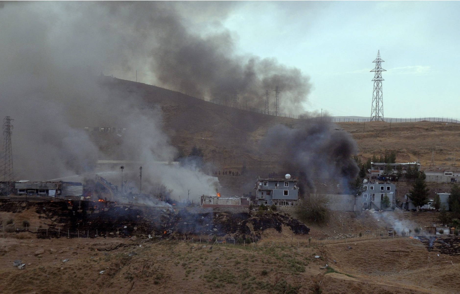 Smoke rises and fires still burn after Kurdish militants attacked a police checkpoint in Cizre, southeast Turkey, Friday, Aug. 26, 2016, with an explosives-laden truck, killing several police officers and wounding dozens more, according to reports from the state-run Anadolu news agency. The attack struck the checkpoint some 50 meters (yards) from a main police station near the town of Cizre, in the mainly-Kurdish Sirnak province that borders Syria. Turkish authorities have put a temporary ban on distribution of images relating to Friday's Cizre attack within Turkey. (IHA via AP) Turkey Kurds