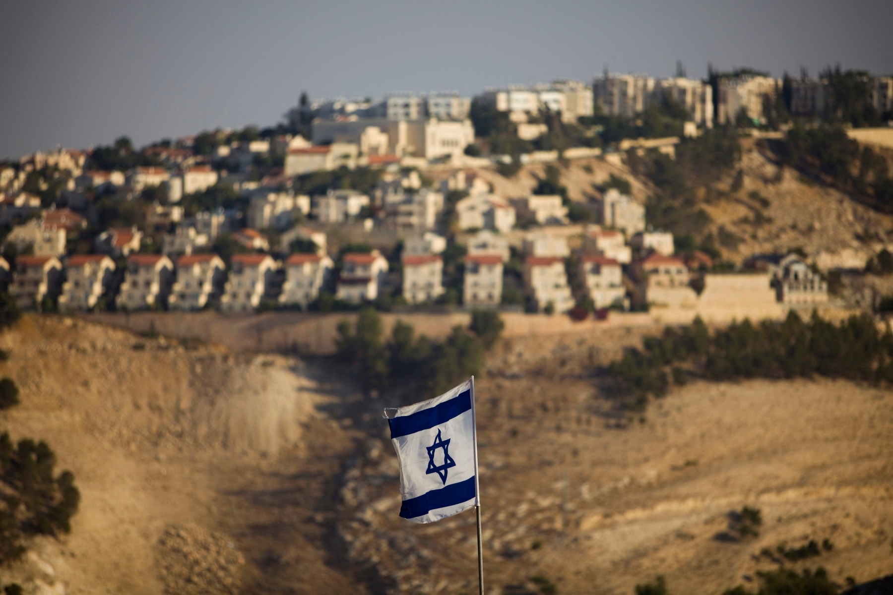 FILE - In this Monday, Sept. 7, 2009 file photo, an Israeli flag is seen in front of the West Bank Jewish settlement of Maaleh Adumim on the outskirts of Jerusalem. The European Union on Wednesday, Nov. 11, 2015 approved guidelines for its member states to specially label products made in West Bank settlements, a move that has already been criticized by Israel. (AP Photo/Bernat Armangue, File) Mideast Europe Israel