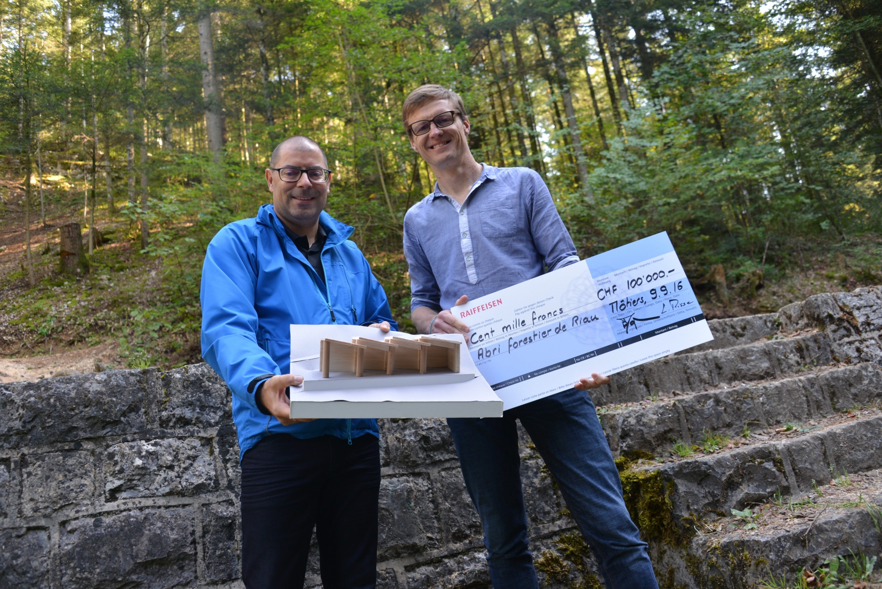 Enzo Macuglia, directeur de la banque Raiffeisen du Val-de-Travers, et Frédéric Mairy, conseiller communal, avec la maquette du futur abri forestier.