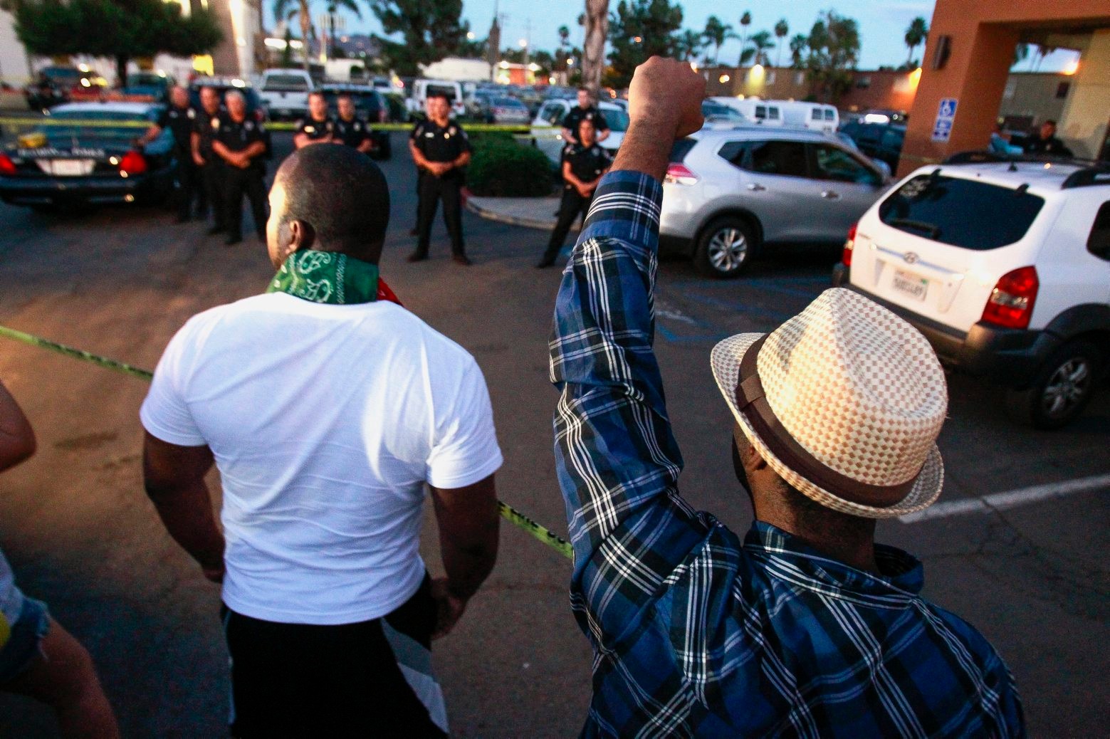 One man holds his fist up as others yell at police at the scene where a black man was shot by police earlier in El Cajon, east of San Diego, Calif., Tuesday, Sept. 27, 2016. (Hayne Palmour IV/The San Diego Union-Tribune via AP) APTOPIX California Police Shooting