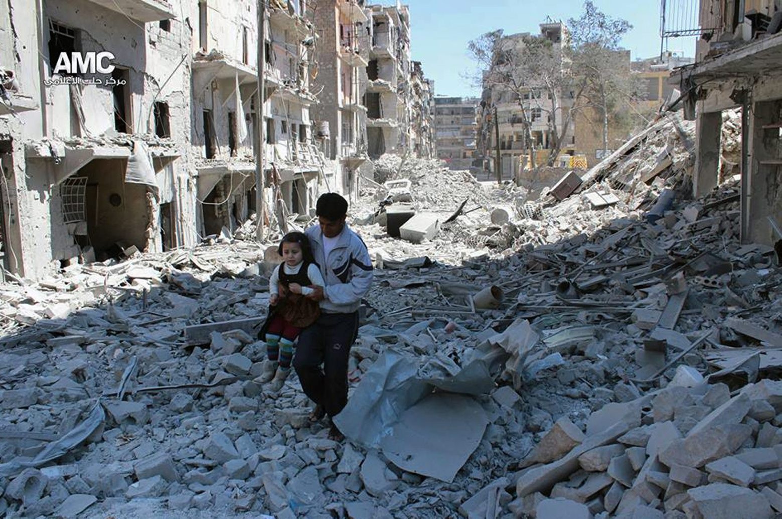 FILE -- In This April 21, 2014, file photo, provided by the anti-government activist group Aleppo Media Center (AMC), which has been authenticated based on its contents and other AP reporting, shows a Syrian man holding a girl as he stands on the rubble of houses that were destroyed by Syrian government forces air strikes in Aleppo, Syria. Nearly 100 children were killed in a single week in Aleppo as Syrian and Russian warplanes sought to bombard into submission the rebel eastern districts of the city that have held out against Syrian government forces for five years. Without hope for the future, no regular schooling and little access to nutritious food, the children of Aleppo and their parents struggle to survive and fear the threat an imminent ground offensive. (AP Photo/Aleppo Media Center AMC, File) Mideast Syria Children Of Aleppo