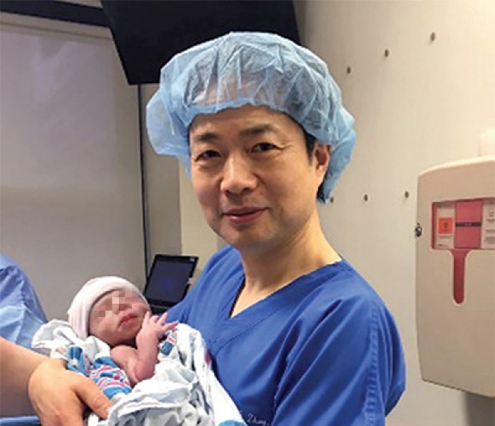 Le médecin John Zhang porte le nouveau né unique au monde.