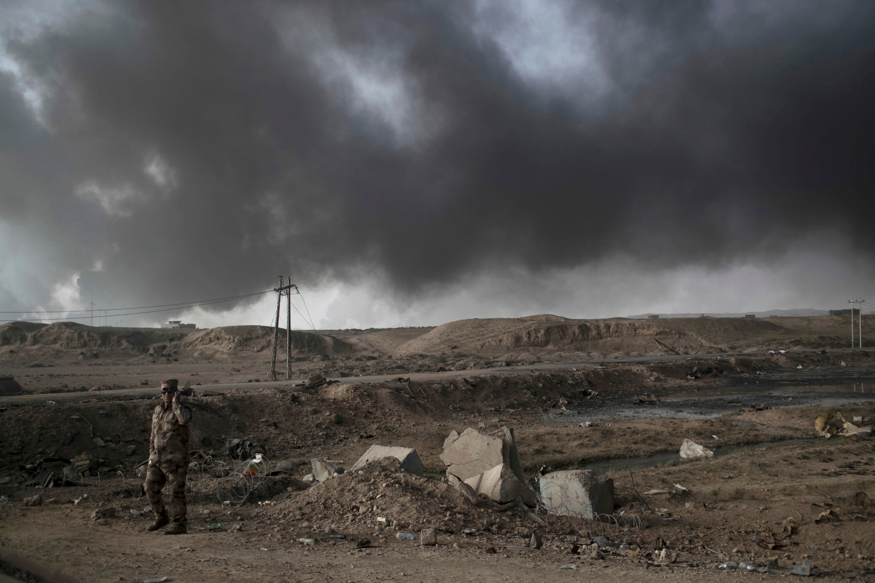 A Iraqi soldier stands near a checkpoint as smoke rises from burning oil fields in Qayara, south of Mosul, Iraq, Tuesday, Nov. 1, 2016. The U.N. human rights office is lauding efforts by the U.S.-led coalition in the battle against the Islamic State group in Mosul. The office in Geneva says coalition flights over Iraq have largely succeeded in preventing IS from bringing in 25,000 more civilians to the city center, where the militant group has been using people as human shields as Iraqi forces advance on Mosul.(AP Photo/Felipe Dana) APTOPIX Mideast Iraq Mosul