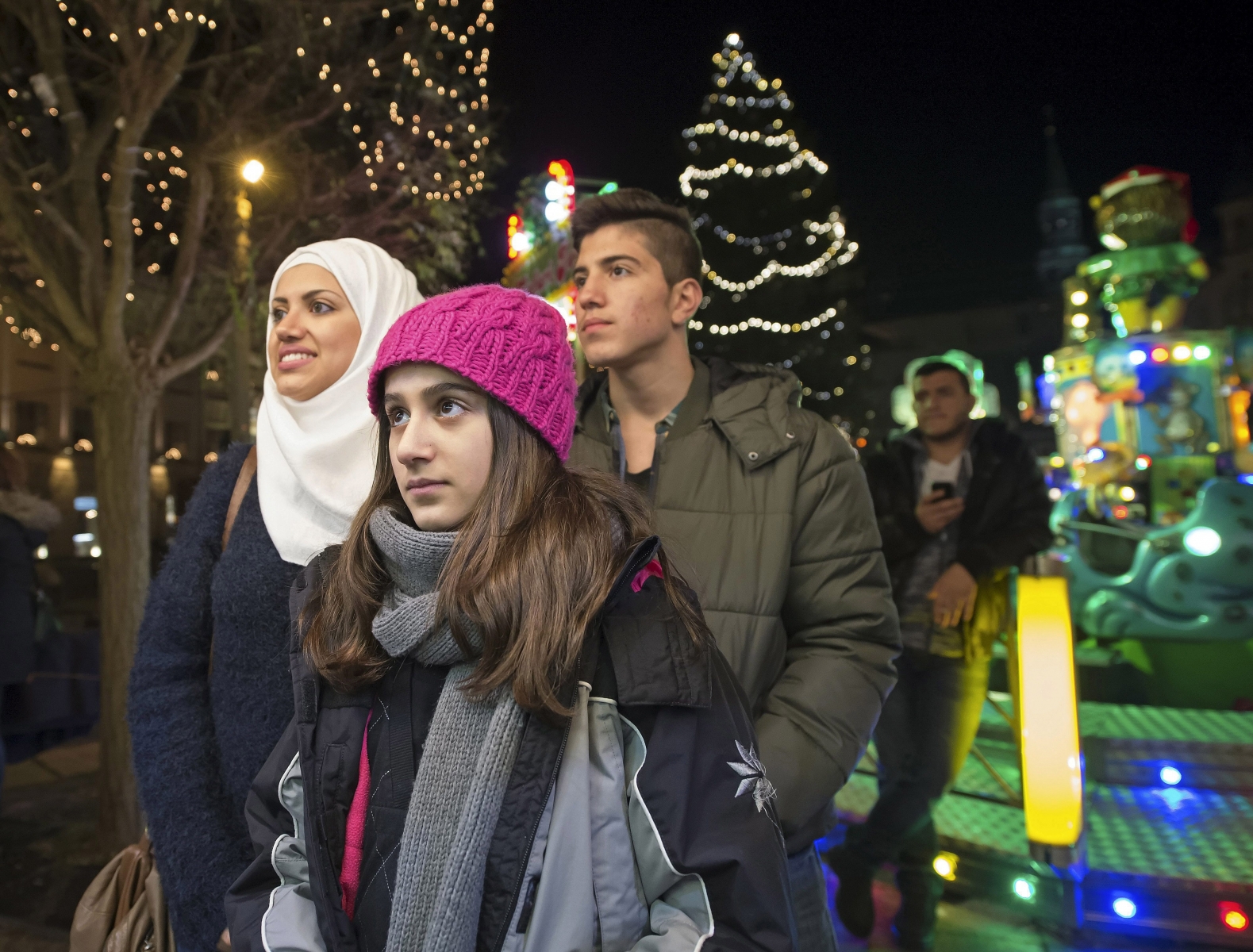In this photo taken Tuesday, Dec. 8, 2015, Syrian refugees Reem Habashieh, Raghad Habashieh, Yaman Habashieh and Mohammed Habashieh, from left to right, visit the Christmas market in Zwickau, eastern Germany. The Muslim family with their mother Khawla Kareem has joined in the Christmas spirit of their neighbors, decorating the door of their flat with glittery red bells and tree branches in green and gold. (AP Photo/Jens Meyer) Germany The New Europeans Refugee Family