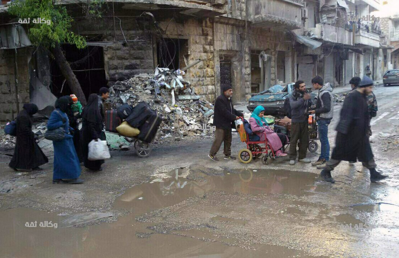 This image released by the Thiqa News Agency, shows civilians gathering for evacuation from eastern Aleppo, Syria, Thursday, Dec. 15, 2016. Syrian activists said residents in eastern Aleppo are starting to board buses and ambulances, the first step in an evacuation that is part of the rebel enclave's effective surrender. (Thiqa News via AP) Mideast Syria