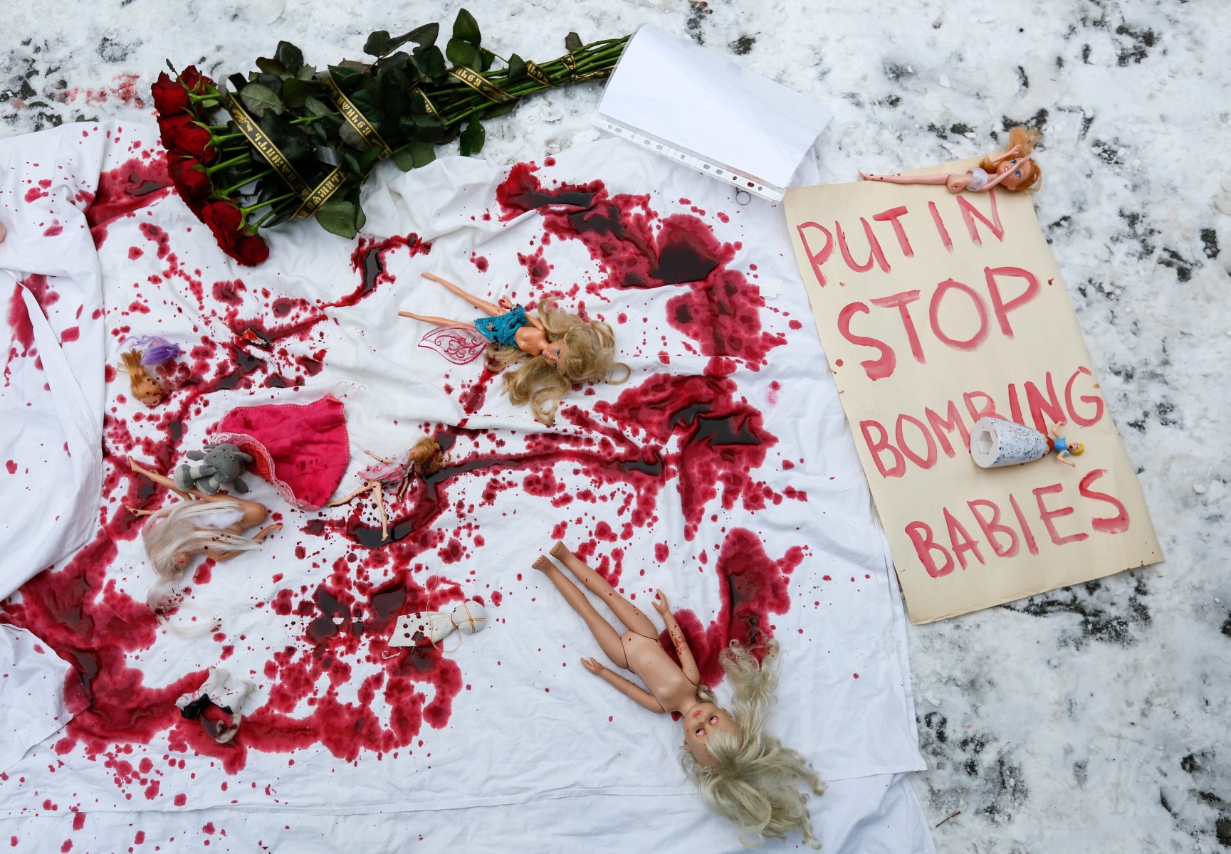epa05676444 A banner with the text 'Putin stop bombing babies' is placed on the ground next to dolls and flowers during a demonstration of activists calling to stop the bombing of Aleppo in Syria, in front of the Russian embassy in Kiev, Ukraine, 15 December 2016. Activists gathered to show solidarity with trapped citizens of Aleppo in Syria and to demand to stop the bombing of Aleppo in Syria.  EPA/ROMAN PILIPEY UKRAINE PROTEST SYRIA ALEPPO