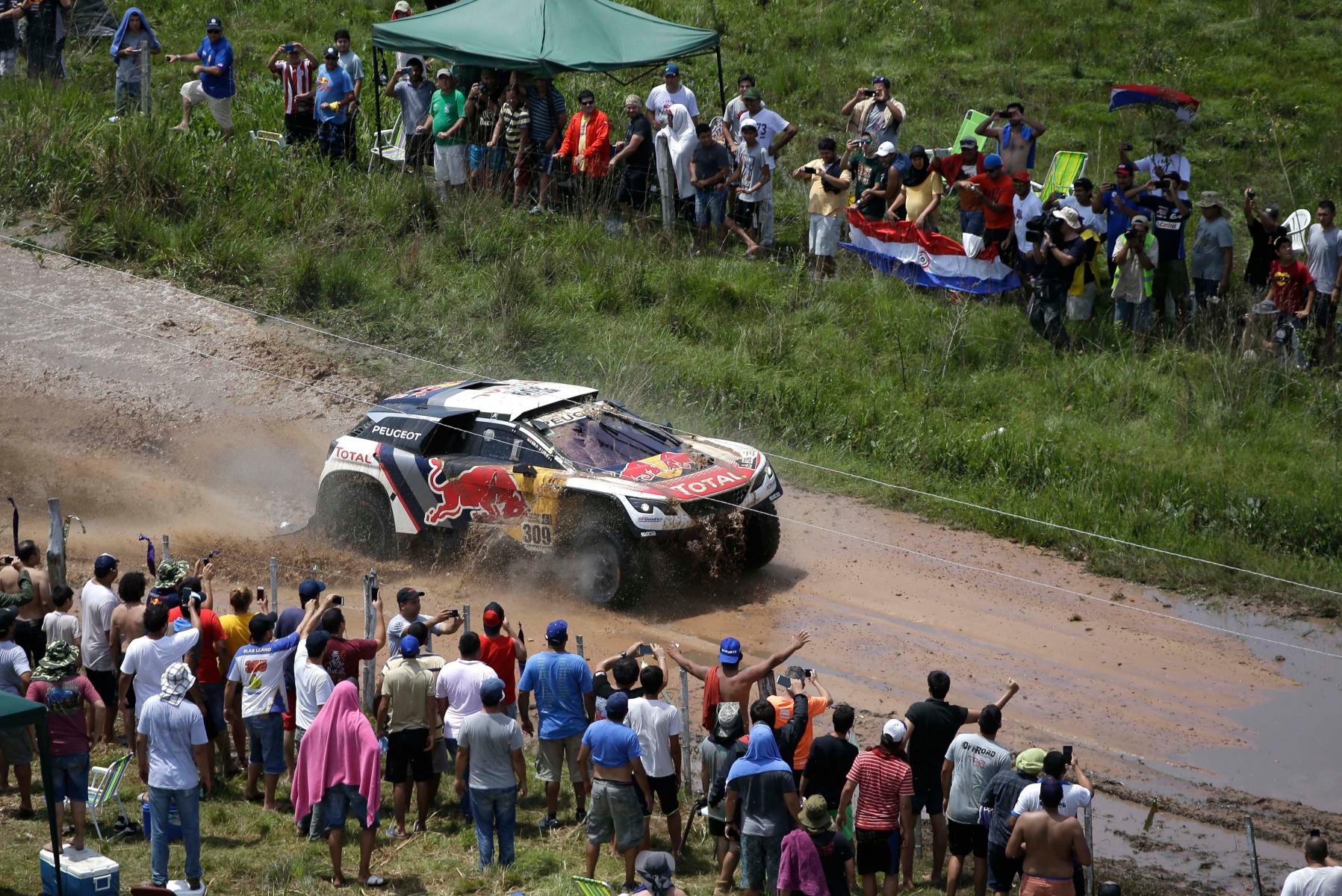 Spectators watch driver Sebastien Loeb, of France, and co-driver Daniel Elena, of Monaco, race their Peugeot during the first stage of the Dakar Rally between Asuncion, Paraguay and Resistencia, Argentina, Monday, Jan. 2, 2017. The race will pass through Bolivia as well. (AP Photo/Martin Mejia) Paraguay Dakar Rally