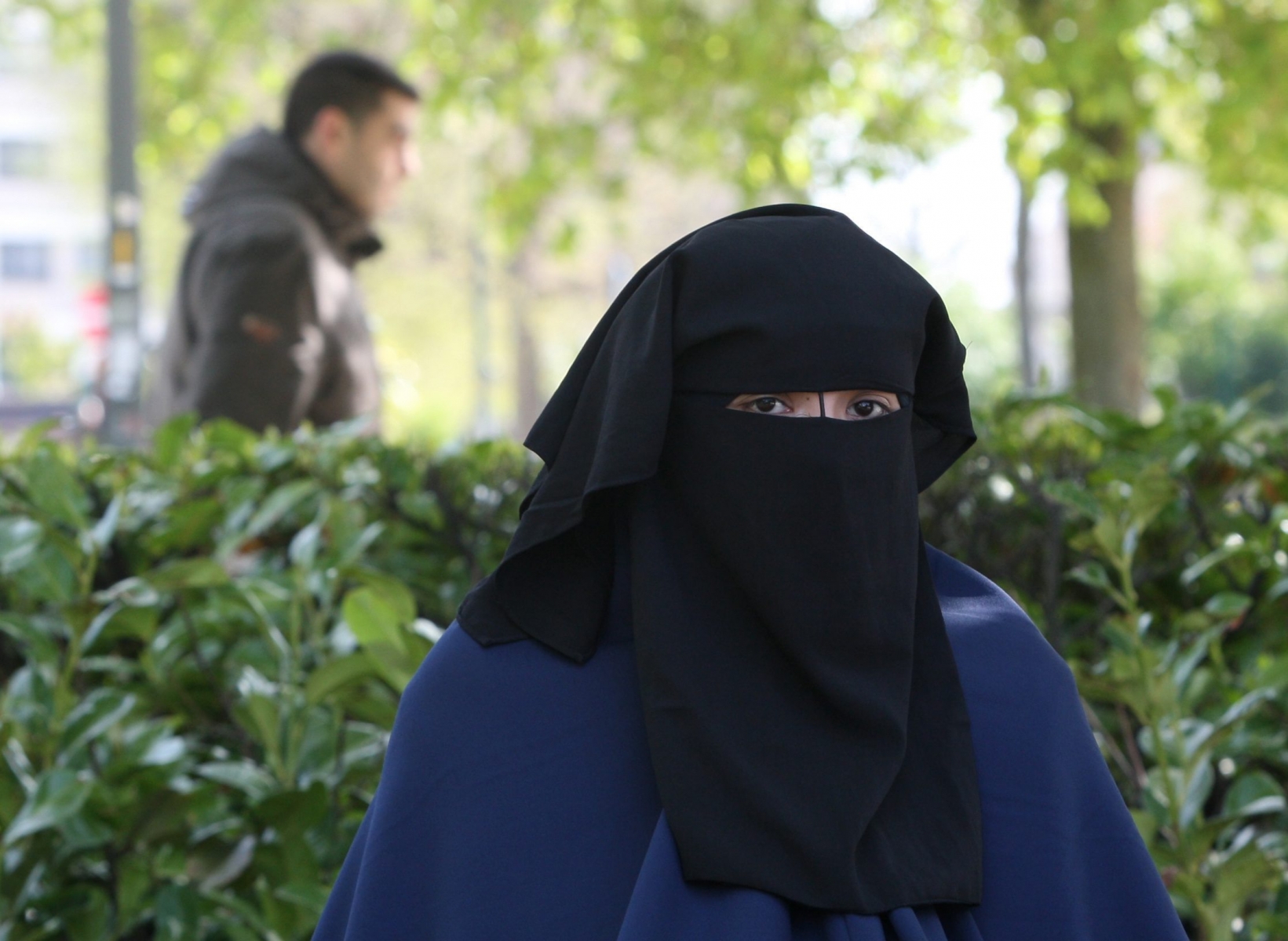 An Egyptian woman wears Islamic " Niqab" , which reveals only the eyes, walks in front of tens of soldiers securing the site of Cairo New court during the verdict of the 26 suspected Hezbollah members, accused of plotting attacks on tourists and shipping in the Suez Canal and sending operatives and explosives to Gaza to help militant groups there, in New Cairo, Egypt, Wednesday, April 28, 2010 . An Egyptian judge has sentenced three suspected Hezbollah members accused of plotting attacks on tourists, including its main Shiite leader, with life in prison. The rest of the suspects received sentences ranging from 15 years to six months. (AP Photo/Amr Nabil)       Mideast Egypt Hezbollah