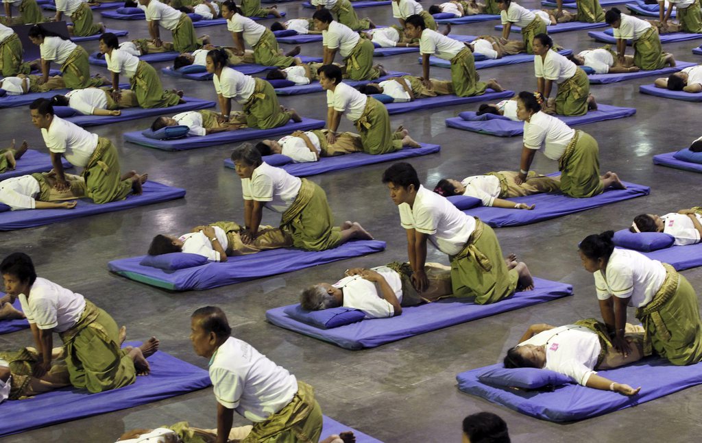 Thai masseuses perform mass masaging at a sport arena on the outskirts of Bangkok, Thailand Thursday, Aug. 30, 2012. Thailand has long been known as the massage capital of the world. Now, it has a Guinness World Record to prove it when some 641 massage therapists mass-massaged 641 people simultaneously for 12 minutes to win the honor Thursday at an indoor arena in Bangkok. The event was organized by the Health Ministry to promote the Southeast Asian nation's massage and spa industry. (AP Photo/Apichart Weerawong)