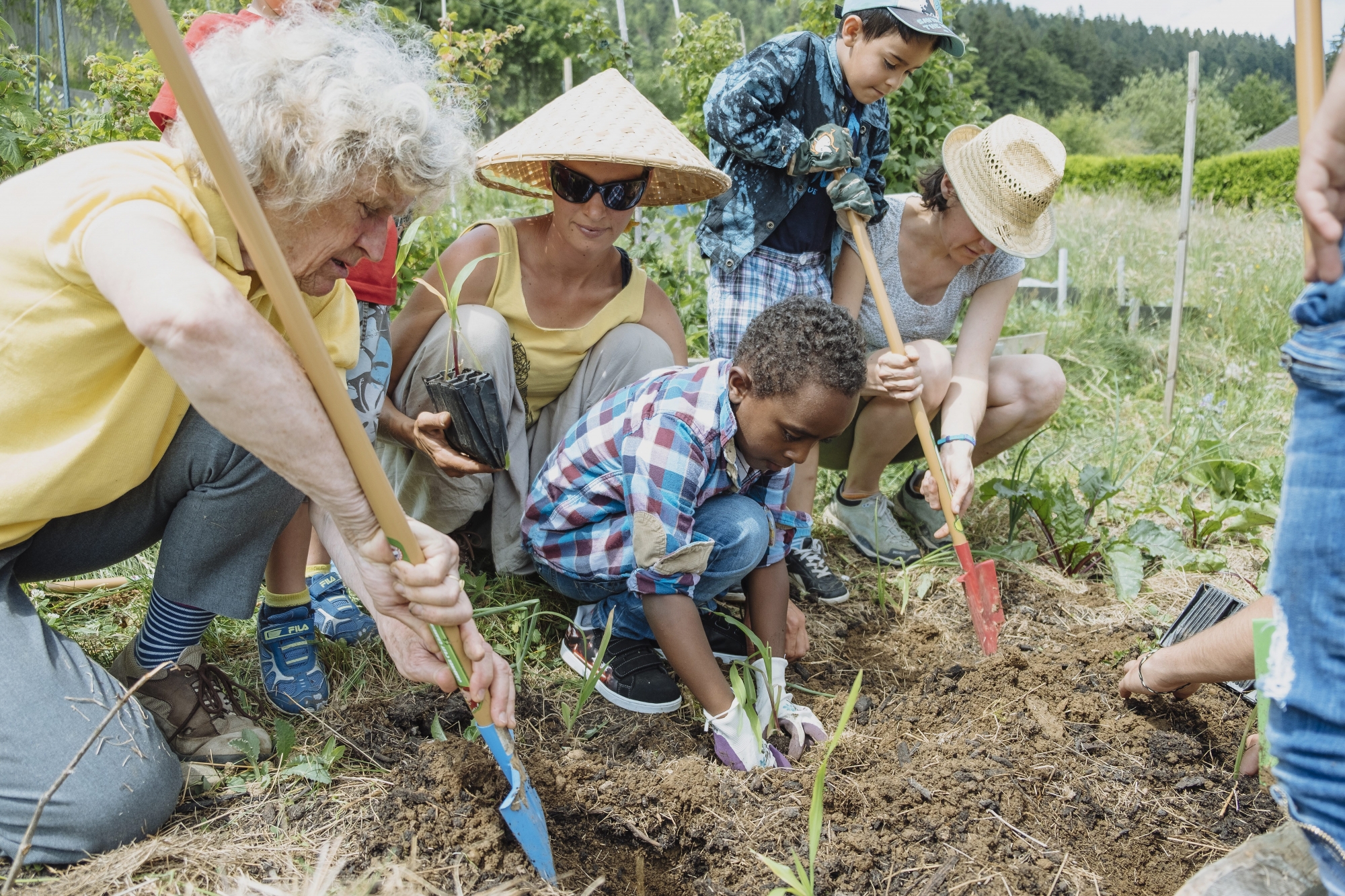 Après avoir enfilé une paire de gants et revêtu un couvre-chef, les enfants requérants et neuchâtelois goûtent aux plaisirs du jardinage.