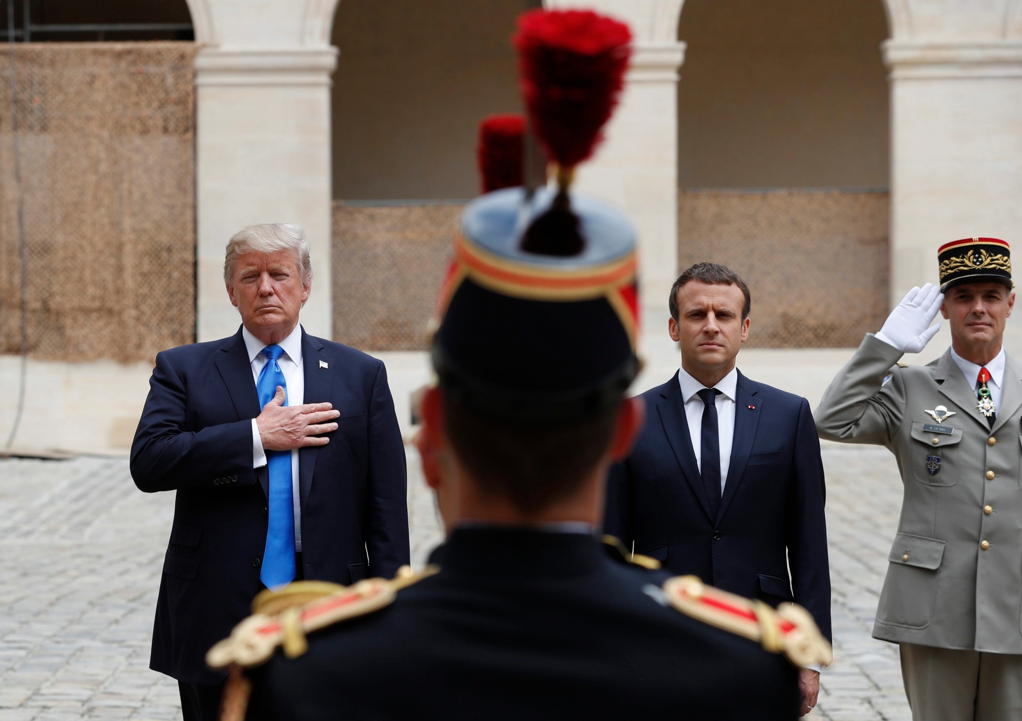 French President Emmanuel Macron and U.S. President Donald Trump, left, listen to national anthems during a welcoming ceremony at Les Invalides in Paris, Thursday, July 13, 2017. Trump and French President Emmanuel Macron are meeting at the Invalides monument for a tour of the golden-domed building housing some of France's greatest war heroes, including Napoleon Bonaparte and the Supreme Allied Commander in World War I. (Yves Herman, Pool via AP) France Trump
