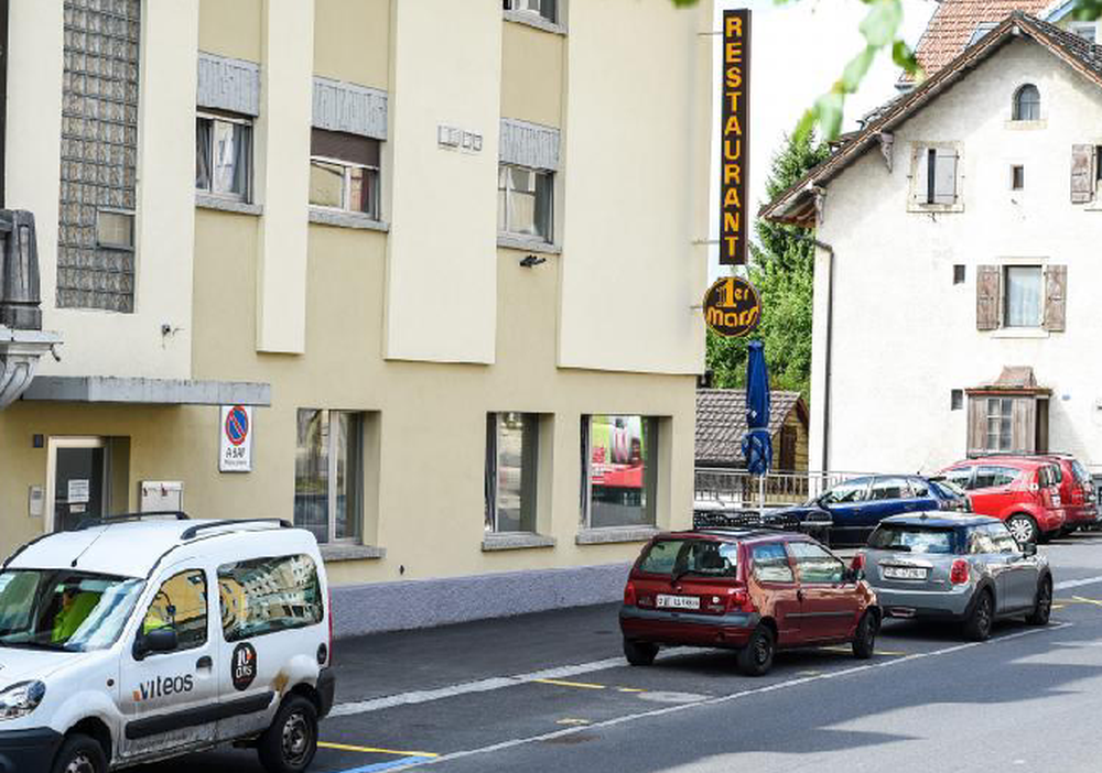 Un habitant de Cernier a repeint en jaune trois places de stationnement devant son immeuble, qui accueille le restaurant du 1er-Mars. Un panneau "places privées" figure sur la façade du bâtiment.