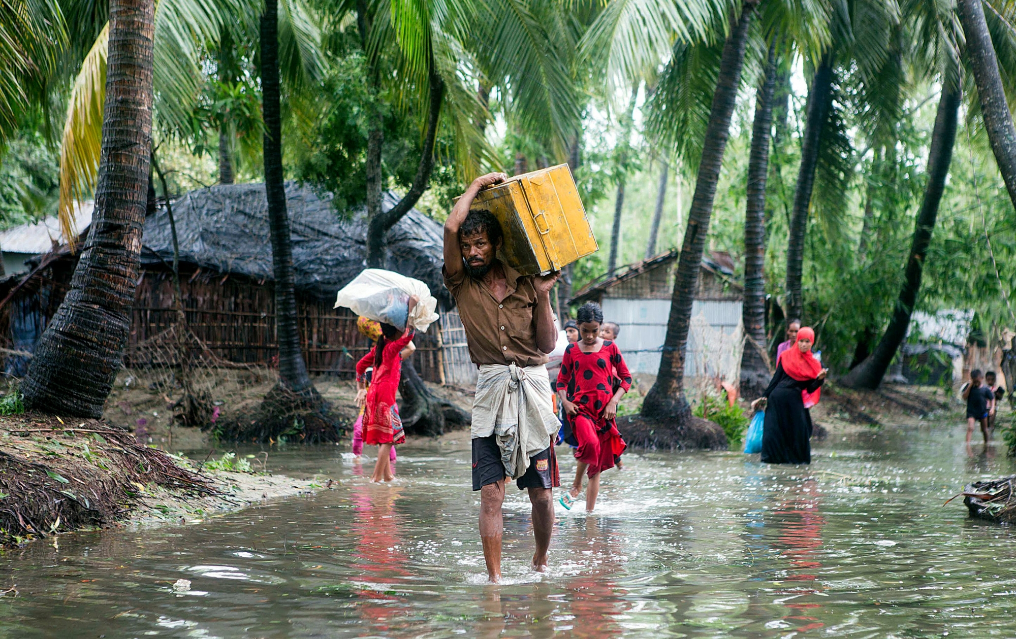 epa05999274 Bangladeshi people walk with their belongings towards a safer area near the coastal line at the Cox's Bazar district in the Chittagong, in Bangladesh, 30 May 2017. At least five dead, 10 injured, and houses damaged after the cyclone Mora hit the southwestern part of Bangladesh, where around two million people were evacuated and the situation is debilitating.  EPA/STR BANGLADESH WEATHER CYCLONE MORA