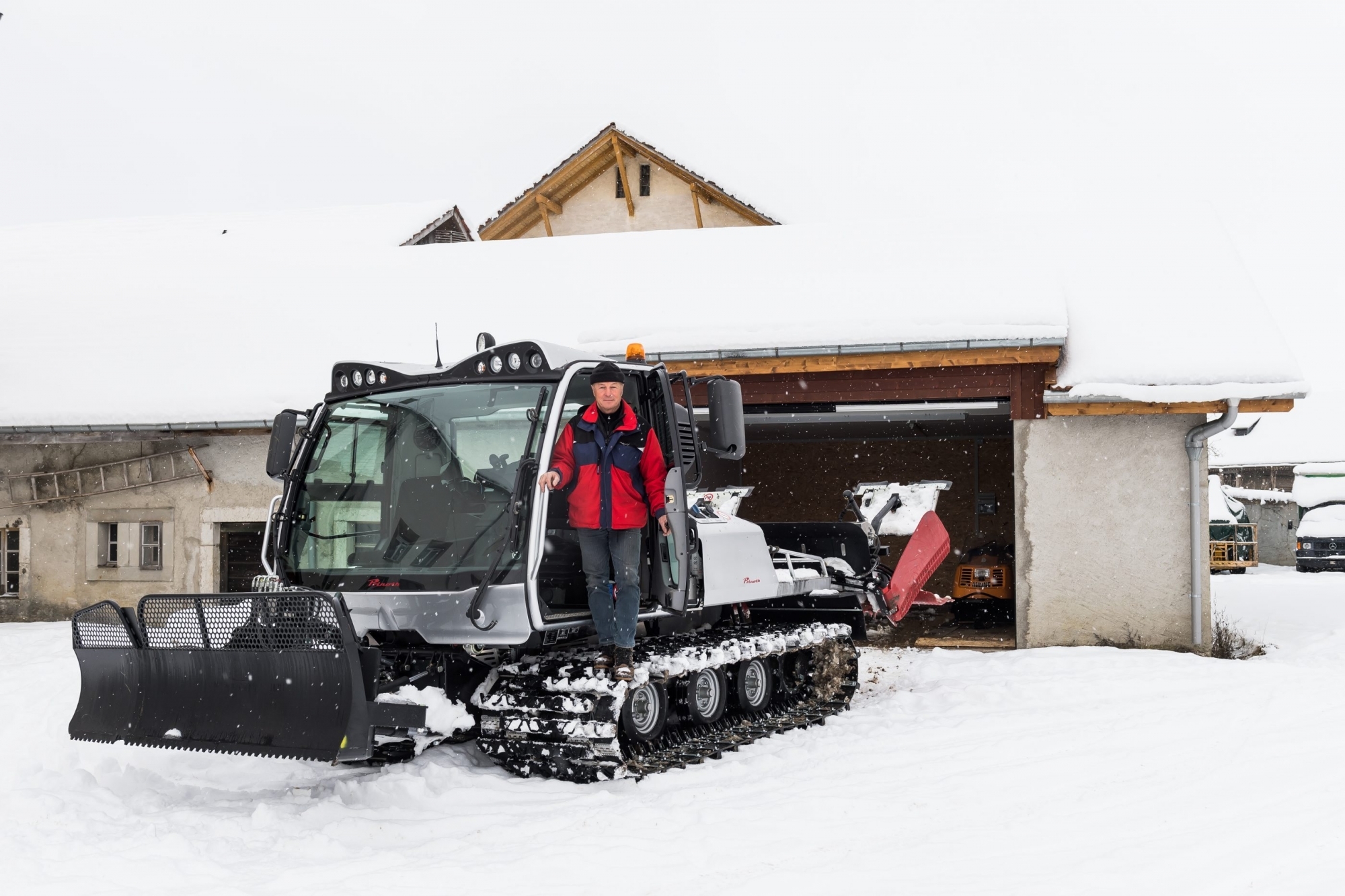 Jean-Pierre Schneider sur la dameuse de La Brévine, devant le nouveau garage du centre nordique. Photo: Lucas Vuitel