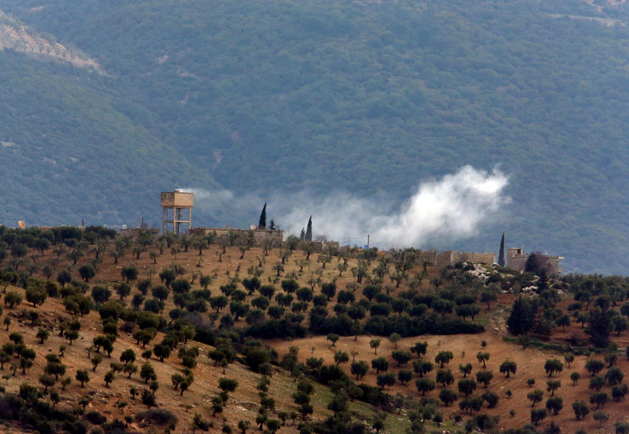 Smoke billows from a position inside Syria, after a Turkish Army artillery fired, as seen from the outskirts of the village of Sugedigi, Turkey, adjacent to the border with Syria, Sunday, Jan. 21, 2018.  Turkey's ground troops entered the enclave of Afrin, in northern Syria on Sunday and were advancing with Turkish-backed Syrian opposition forces in their bid to oust Syrian Kurdish forces from the region.(AP Photo/Lefteris Pitarakis) Turkey Syria
