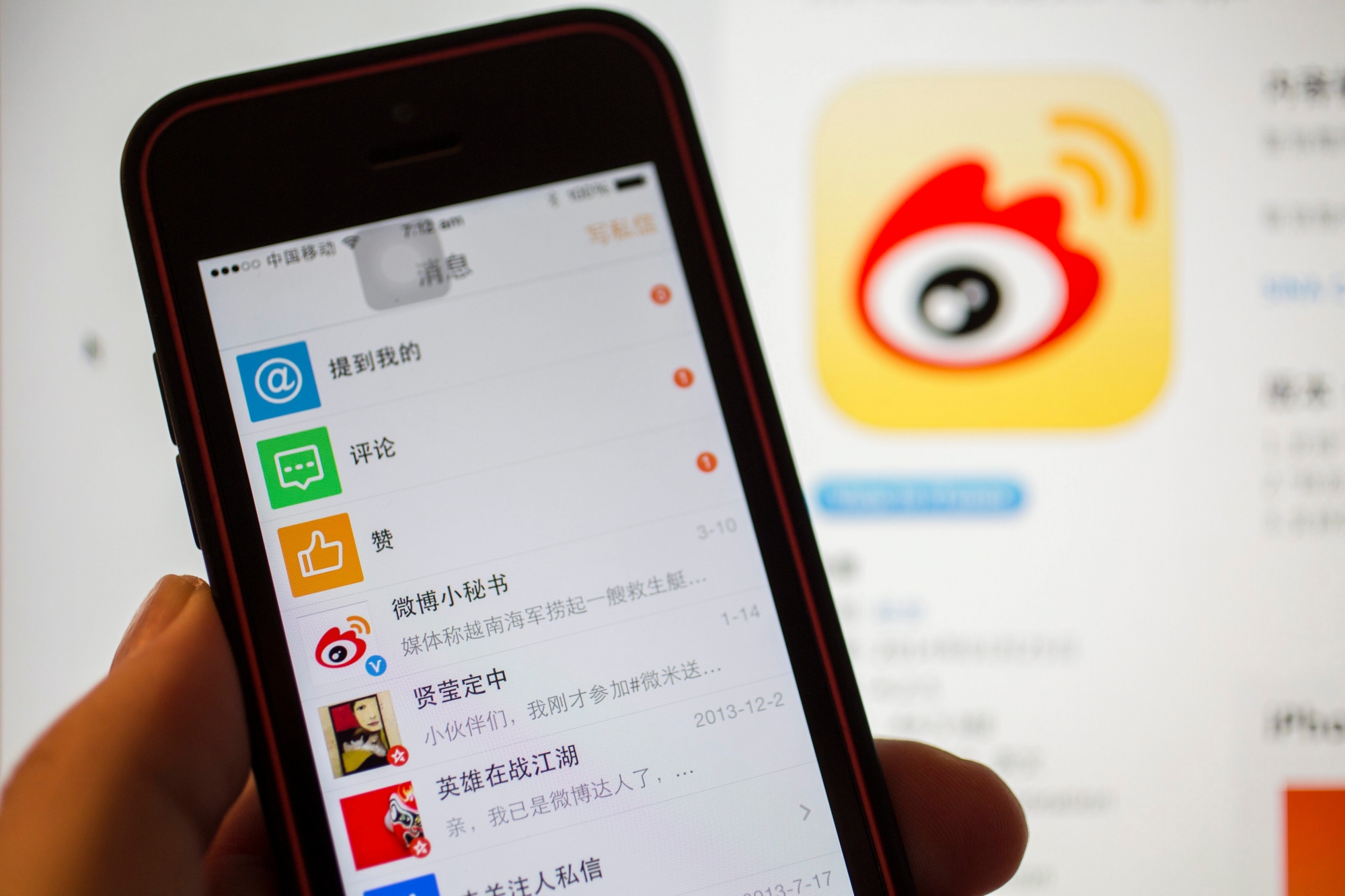 epa04129215 A smartphone running the Sina Weibo social networking app is seen against a background of the company logo on screen in Beijing, China, 17 March 2014. Sina Weibo is one of a number of large Chinese technology companies preparing for initial public offerings (IPO) this year.  EPA/ADRIAN BRADSHAW CHINA SINA WEIBO