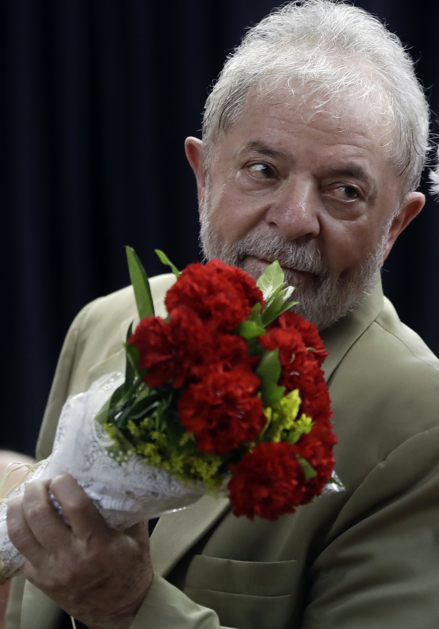 Former Brazilian President Luiz Inacio Lula da Silva holds a bouquet of flowers that he received from a supporter, during the launch of his book in Sao Paulo, Brazil, Friday, March 16, 2018. In his book entitled "Truth Will Triumph: The People Know Why I am Being Condemned," Lula da Silva says he is ready to go to jail and serve a 12 year and one month sentence on corruption charges. (AP Photo/Andre Penner) Brazil Ex President Book