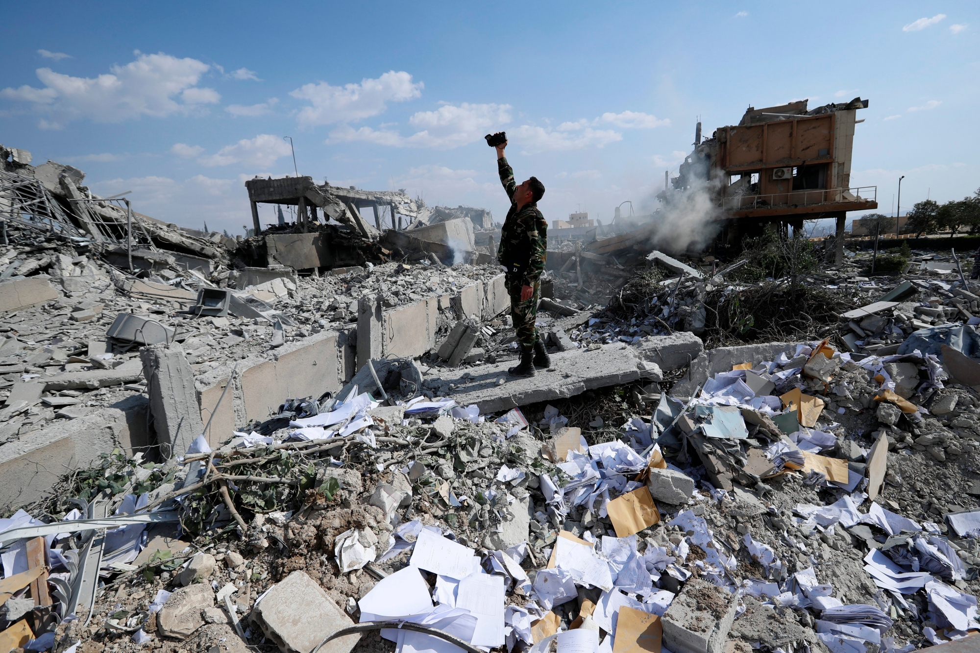 A Syrian soldier films the damage of the Syrian Scientific Research Center which was attacked by U.S., British and French military strikes to punish President Bashar Assad for suspected chemical attack against civilians, in Barzeh, near Damascus, Syria, Saturday, April 14, 2018. The Pentagon says none of the missiles filed by the U.S. and its allies was deflected by Syrian air defenses, rebutting claims by the Russian and Syrian governments. Lt. Gen. Kenneth McKenzie, the director of the Joint Staff at the Pentagon, also says there also is no indication that Russian air defense systems were employed early Saturday in Syria. (AP Photo/Hassan Ammar) APTOPIX Syria