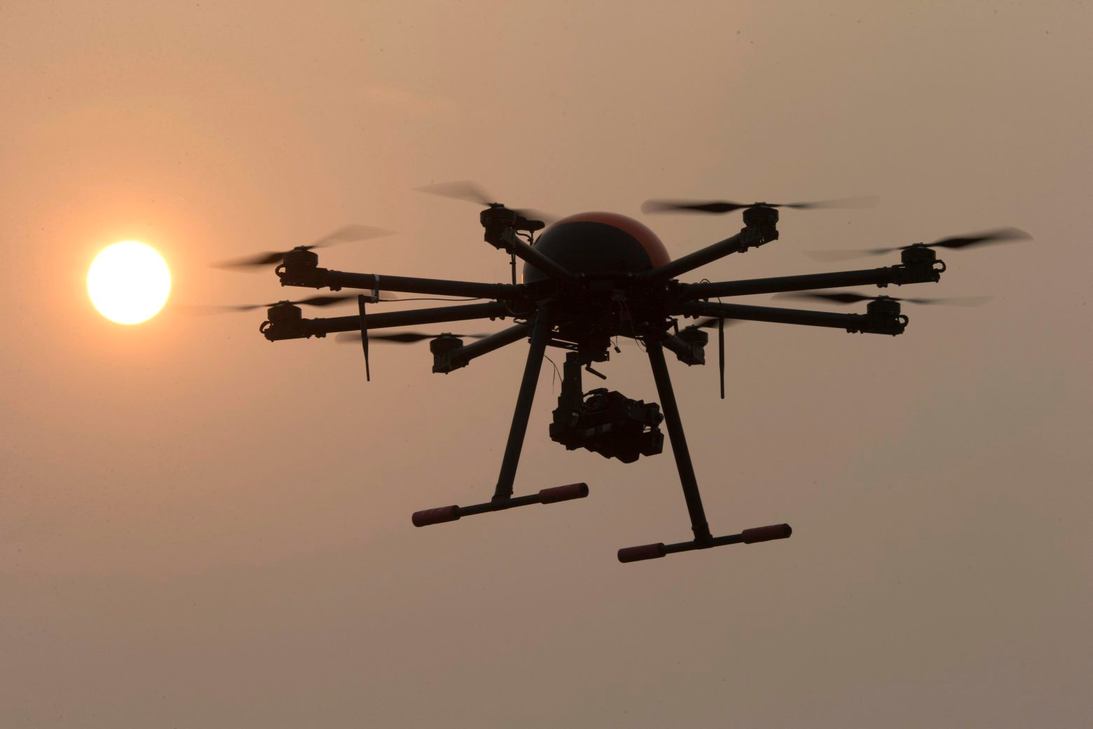 In this Oct. 17, 2015 photo, a drone hovers with the sun in the background near a school run by TT Aviation Technology in Beijing. TT Aviation Technology Co. - and their instructors - are part of a new cottage industry sprouting up in China, where drones are being deployed in rising numbers and touted as a game-changer in agriculture, logistics, film production and law enforcement. (AP Photo/Ng Han Guan) CHINA DRONE SCHOOL