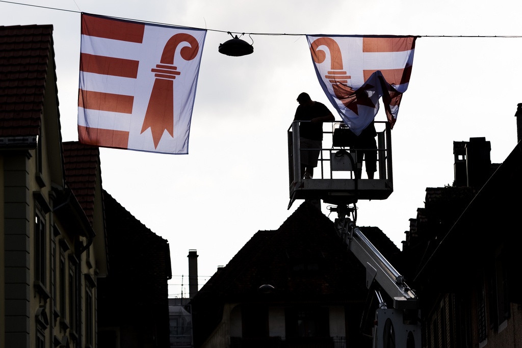 Deux personnes accrochent le drapeau du Jura dans la ville lors de la "Fete de la liberte" ce samedi 16 juin 2018 à Moutier.