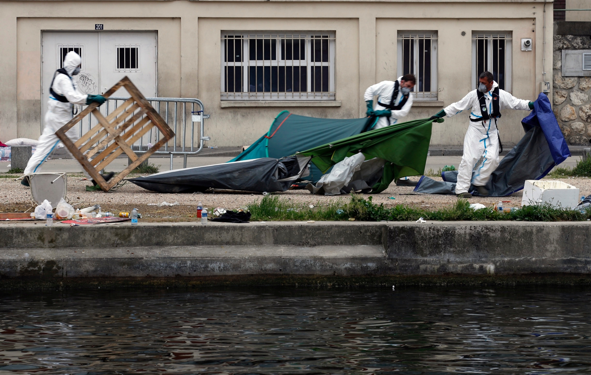 Employees remove tents to clear out a makeshift migrant camp along side of the canal Saint Martin, in central Paris, France, Monday, June 4, 2018. French police have evacuated around 500 migrants, mostly Afghans but some Africans from a makeshift tent encampment. (AP Photo/Francois Mori) France Migrants