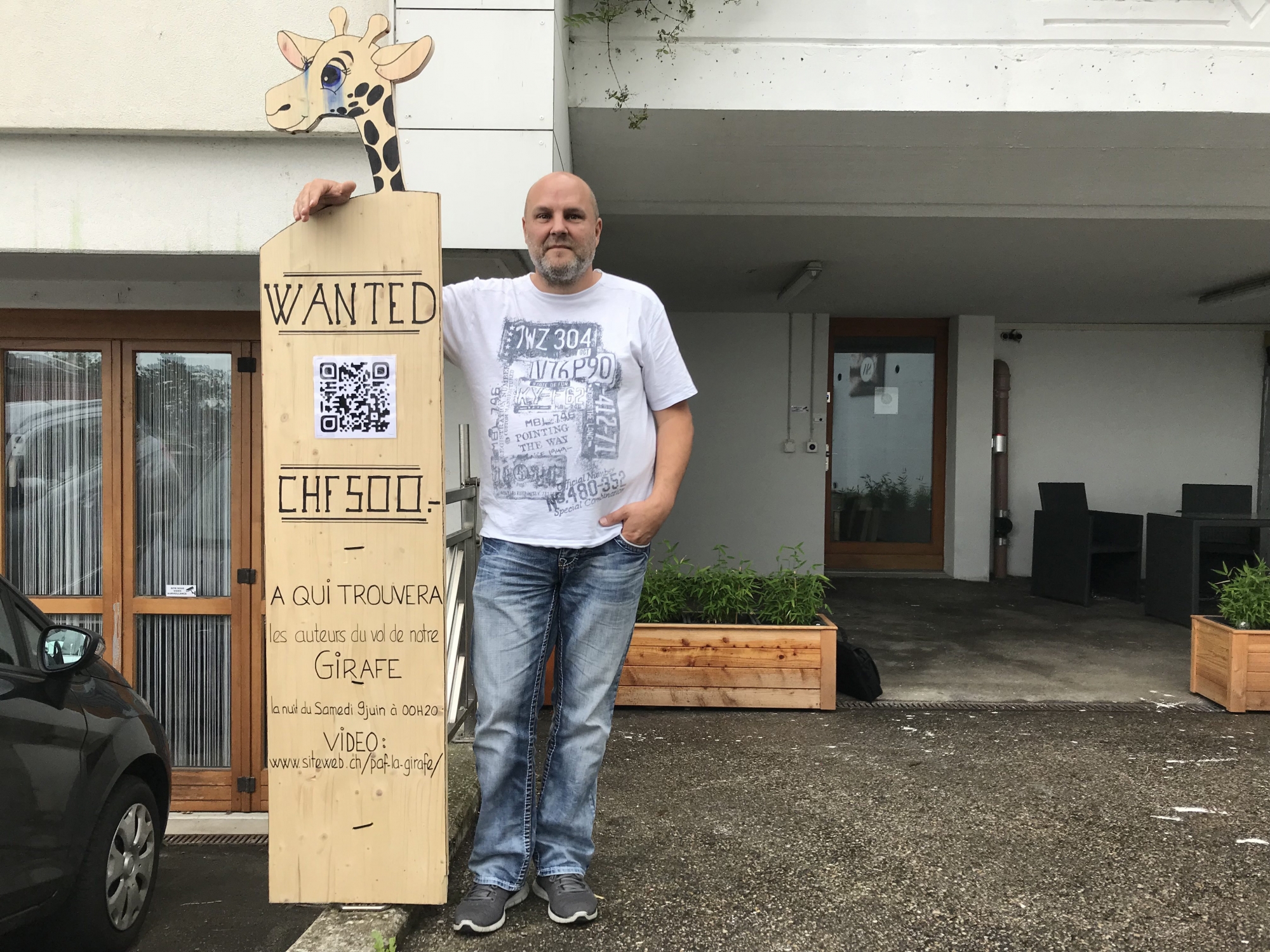 Raphaël Vallat, patron de siteweb.ch pose à côté du panneau "Wanted" qu'il a confectionné après le vol de la girafe mascotte de l'entreprise.