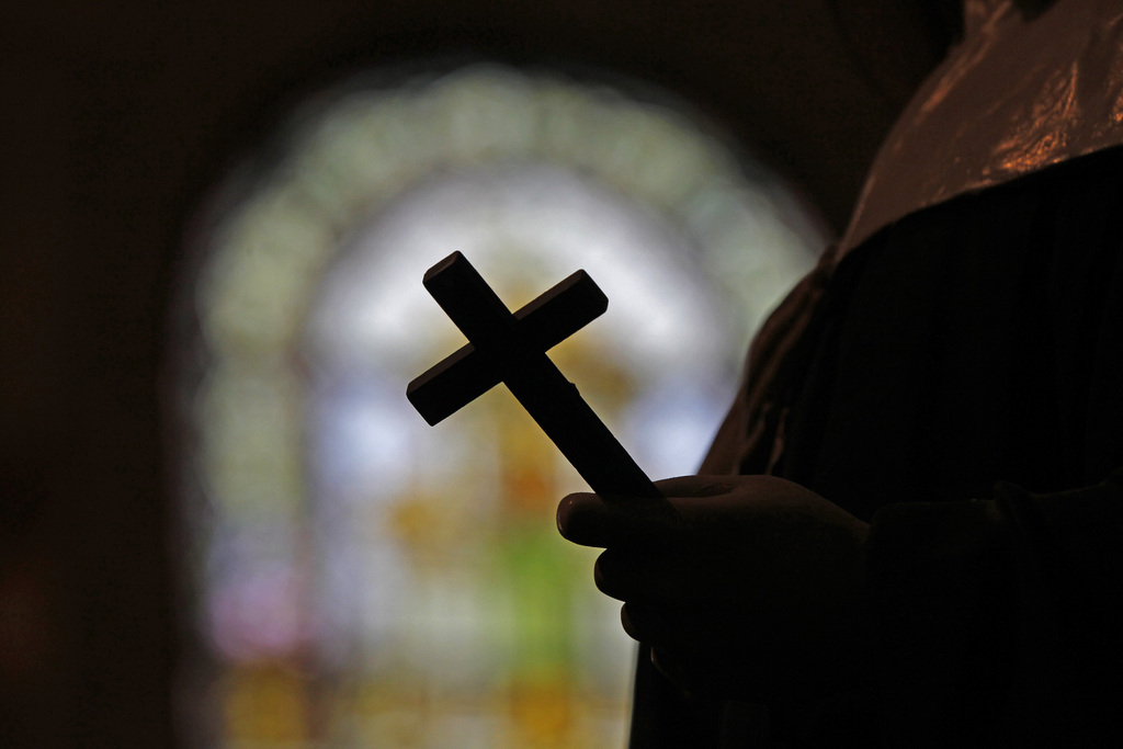 This Dec. 1, 2012 photo shows a silhouette of a crucifix and a stained glass window inside a Catholic Church in New Orleans. A Louisiana Supreme Court decision reaffirmed in May 2014 has revived a sex abuse lawsuit in which parents are suing a priest and a Baton Rouge Catholic diocese for not reporting the alleged abuse when the teenager told the priest about it, and the ruling could have a priest asked to testify about what was said in a private confession. (AP Photo/Gerald Herbert)