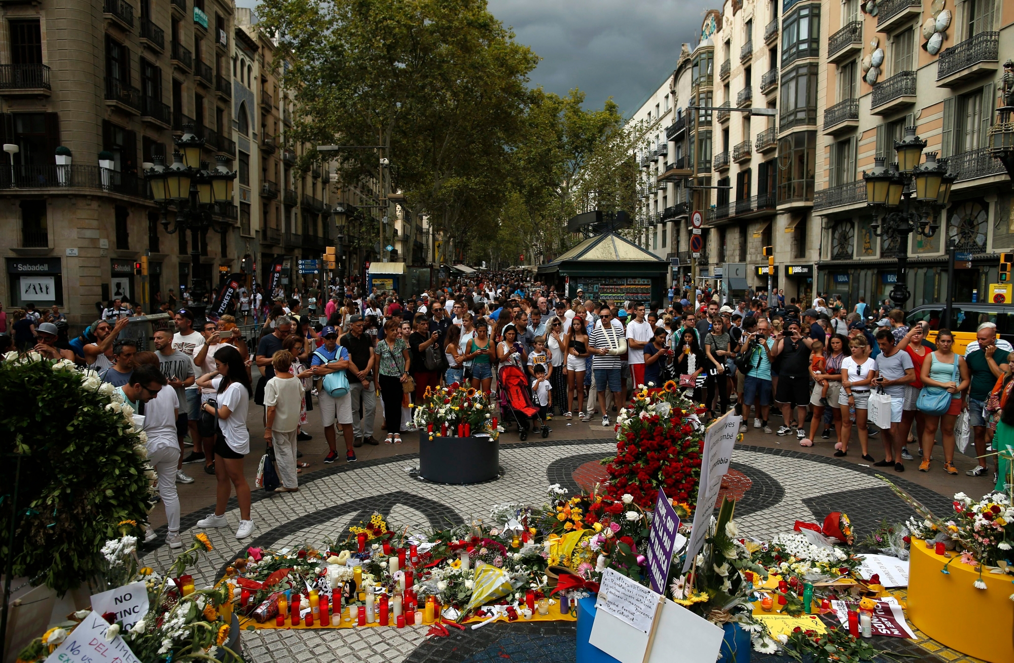 People gather next to at floor mosaic by Catalan artist Joan Miro where the van driven by the attacker stopped in Barcelona, Spain, Friday, Aug. 17, 2018. Barcelona on Friday marked the first anniversary of terror attacks that killed 16 people, with commemorations attended by Spain's King Felipe VI, Queen Letizia, Prime Minister Pedro Sanchez, other government officials and hundreds of people. (AP Photo/Manu Fernandez) Spain Attacks Anniversary