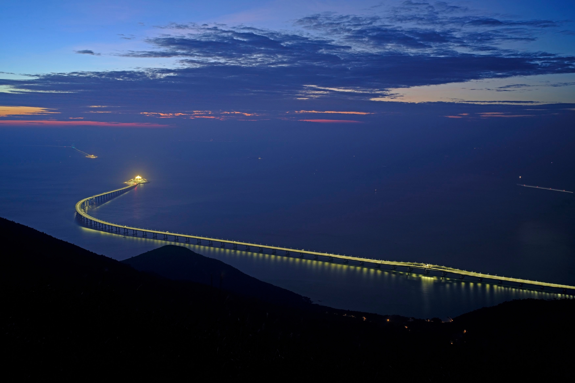 In this Sunday, Oct. 21, 2018, photo, the Hong Kong-Zhuhai-Macau Bridge is lit up in Hong Kong. The bridge, the world's longest cross-sea project, which has a total length of 55 kilometers (34 miles), will have opening ceremony in Zhuhai on Oct. 23. (AP Photo/Vincent Yu) Hong Kong Zhuhai Macau Bridge