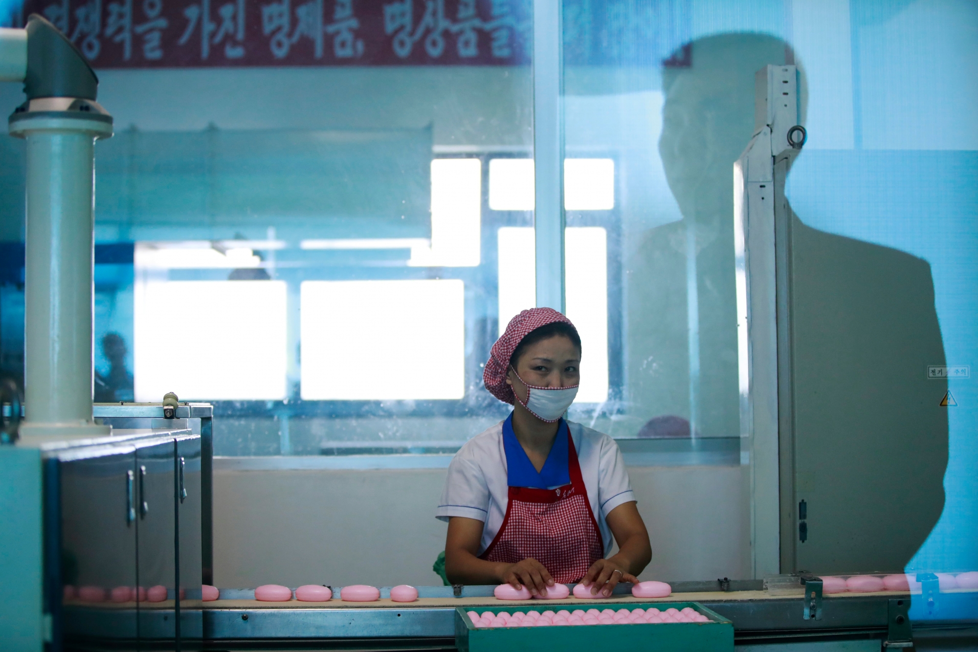 epa07134708 (FILE) - A North Korean man is reflected in a glass window as a female employee works on the production line for soap at the Pyongyang Cosmetics Factory during a tour for foreign media in Pyongyang, North Korea, 08 September 2018 (reissued 01 November 2018). According to a report by Human Rights Watch on 01 November, women in North Korea are subjected to widespread sexual abuse by officials. The report is based on interviews conducted with refugees from the reclusive country, detailing accounts of reape and sexual abuse that have become 'normal' and an accepted part of life to oridnary women.  EPA/HOW HWEE YOUNG (FILE) NORTH KOREA SEXUAL ABUSE