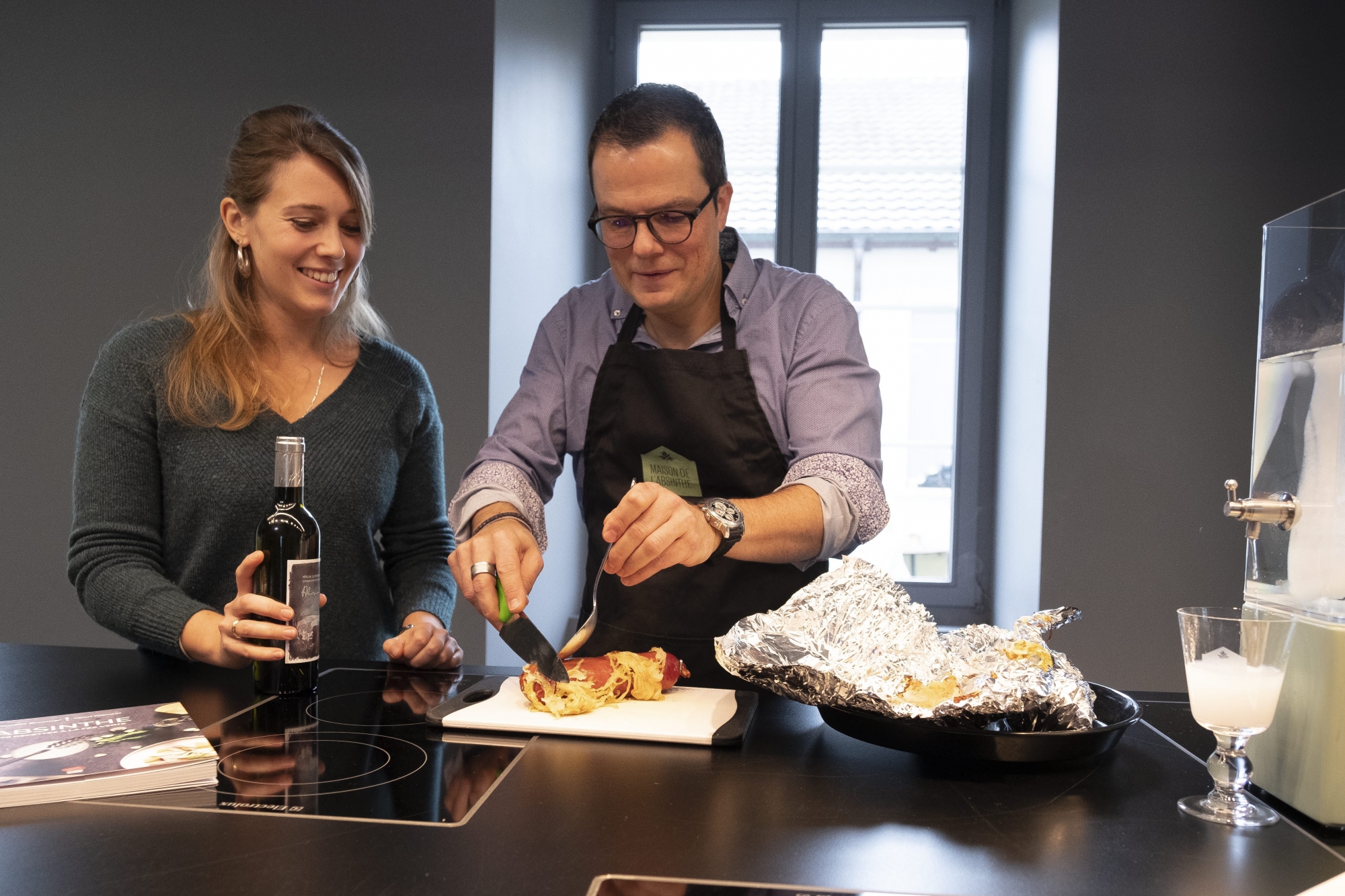 Les auteurs Aurélie Brunner et Yann Klauser en train de déballer un saucisson arrosé à l'absinthe dans les cuisines de la Maison de l'absinthe.