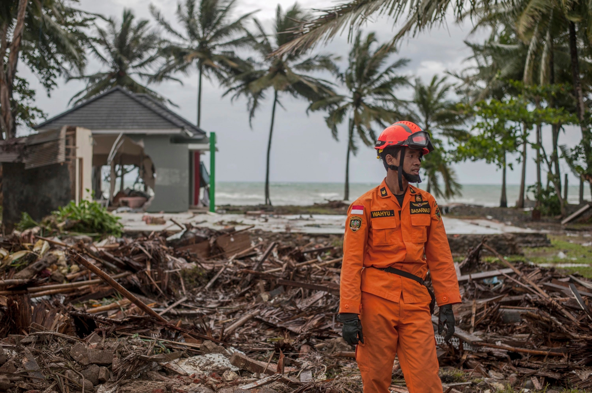A rescuer stands amid debris at a tsunami-ravaged area in Carita, Indonesia, Sunday, Dec. 23, 2018. The tsunami occurred after the eruption of a volcano around Indonesia's Sunda Strait during a busy holiday weekend, sending water crashing ashore and sweeping away hotels, hundreds of houses and people attending a beach concert. (AP Photo/Fauzy Chaniago) Indonesia Tsunami