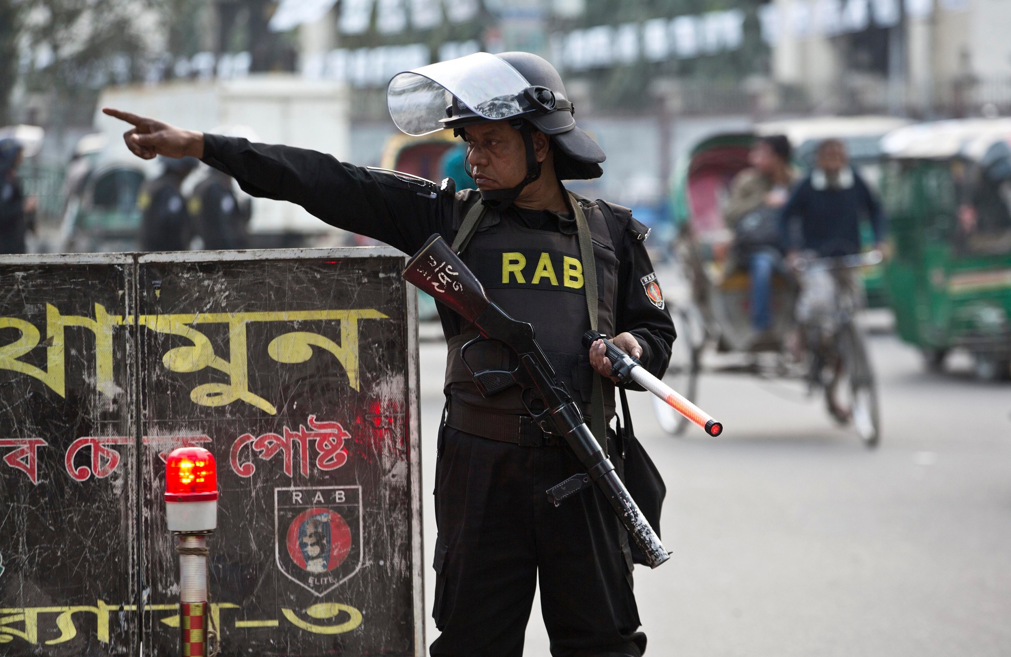 Bangladesh police's elite Rapid Action Battalion (RAB) personal gestures towards a vehicle to stop for checking ahead of the general elections in Dhaka, Bangladesh, Friday, Dec. 28, 2018. Bangladesh Prime Minister Sheikh Hasina is poised to win a record fourth term in Sunday's elections, drumming up support by promising a development bonanza as her critics question if the South Asian nation's tremendous economic success has come at the expense of its already fragile democracy. (AP Photo/Anupam Nath) Bangladesh Elections