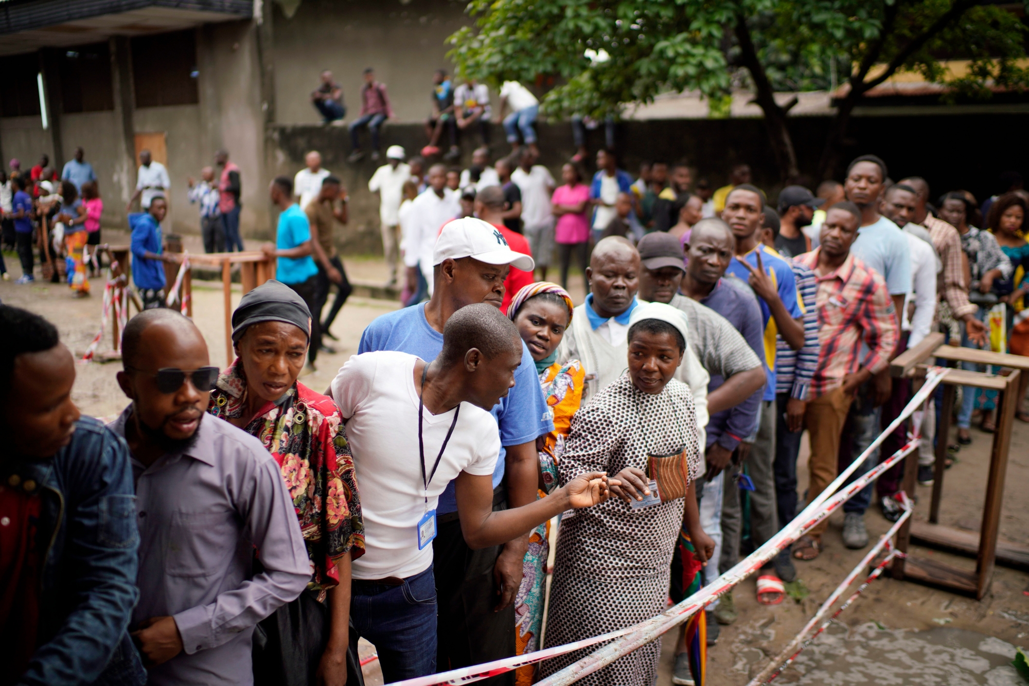 Congolese voters who have been waiting at the St. Raphael school in the Limete district of Kinshasa Sunday Dec. 30, 2018, line up to vote after the voters listings were finally posted five hours after the official start of voting.  Some forty million voters are registered for a presidential race plagued by years of delay and persistent rumors of lack of preparation. (AP Photo/Jerome Delay) Congo Elections